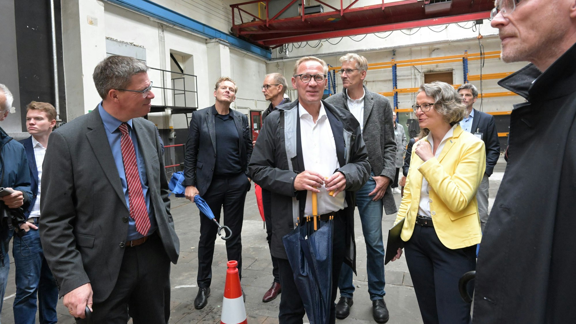 Eine Frau steht mit vielen Männern in einer Halle der ehemaligen Papierfabrik Zanders in Bergisch Gladbach.