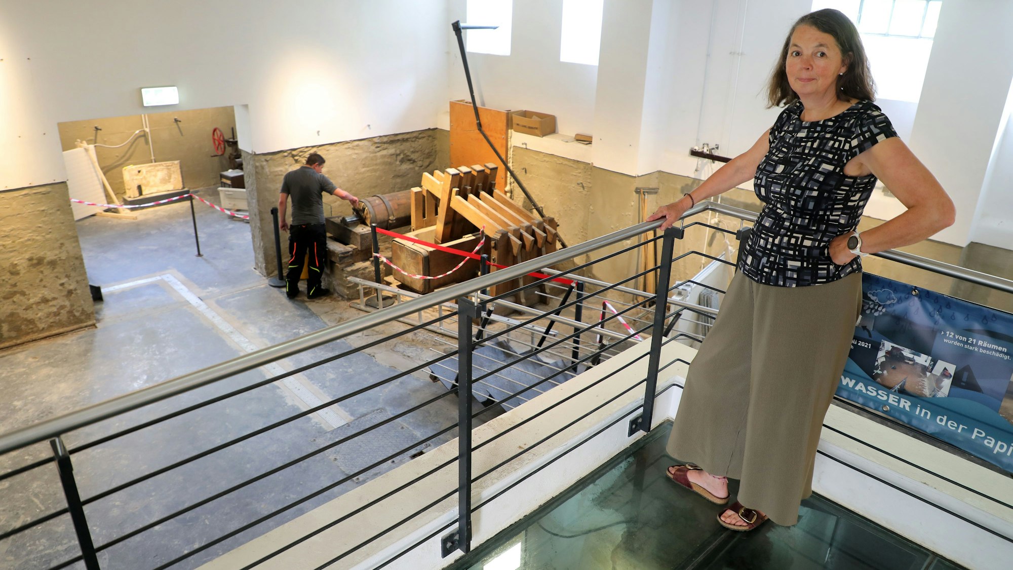 Eine Mitarbeiterin des Museums steht an der Halle mit der Lumpenstampfe des LVR-Industriemuseums Papiermühle Alte Dombach in Bergisch Gladbach.