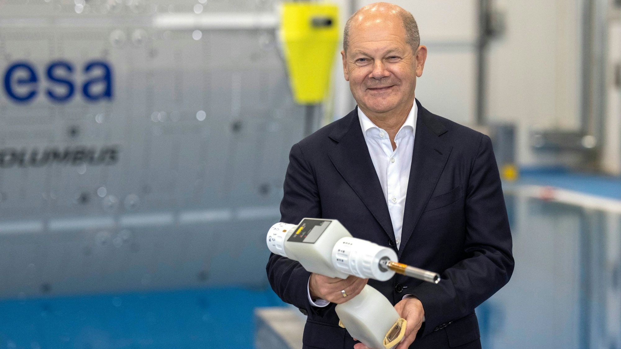 Bundeskanzler Olaf Scholz (SPD) hält einen Akkuschrauber in der Hand, der ein Teil der Astronautenausrüstung ist während seines Besuchs des Deutschen Zentrum für Luft- und Raumfahrt (DLR) und des Astronautenzentrums der Europäischen Weltraumorganisation ESA.