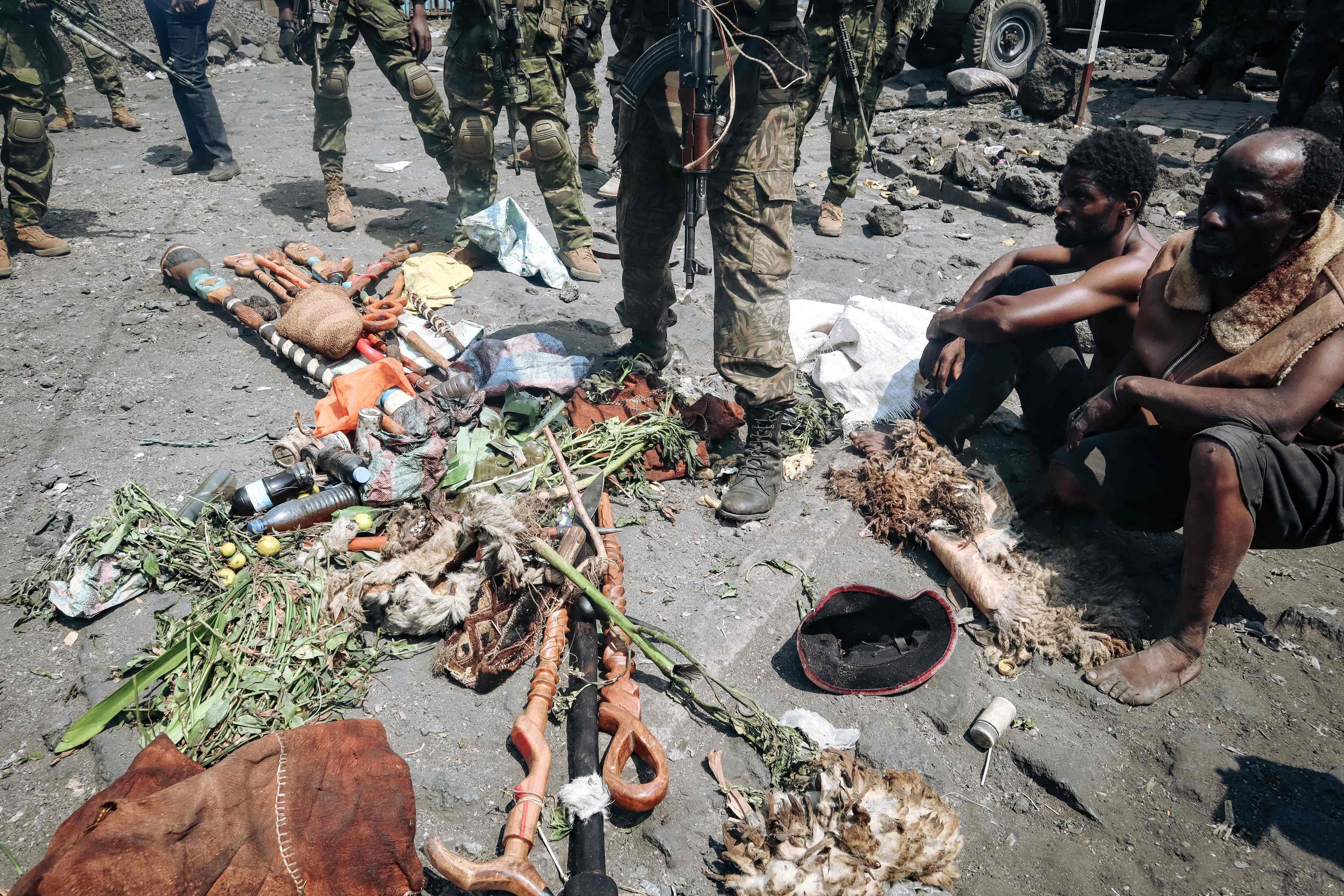 People arrested during a military operation to prevent a planned demonstration against the United Nations by a religious sect, sit in front of their traditional fetishes on the ground and guarded by the army in Goma, eastern Democratic Republic of Congo on August 30, 2023. At least 48 people have been killed and 168 arrested in a crackdown on an anti-UN protest in eastern DR Congo, according to sources and official documentation. On August 30, 2023, Congolese soldiers stopped a religious sect from holding a demonstration against United Nations peacekeepers in the city of Goma. (Photo by AFP)