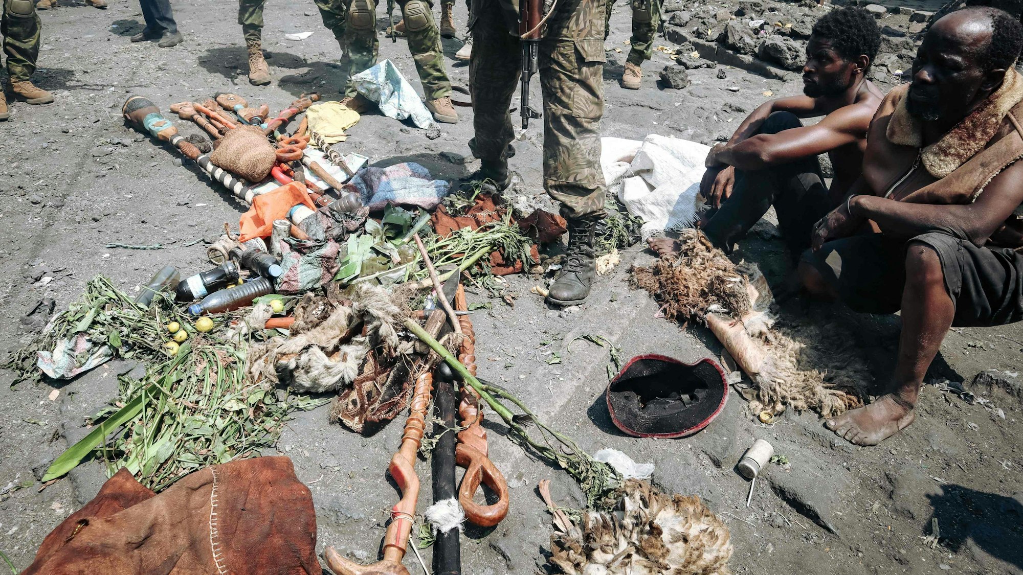 People arrested during a military operation to prevent a planned demonstration against the United Nations by a religious sect, sit in front of their traditional fetishes on the ground and guarded by the army in Goma, eastern Democratic Republic of Congo on August 30, 2023. At least 48 people have been killed and 168 arrested in a crackdown on an anti-UN protest in eastern DR Congo, according to sources and official documentation. On August 30, 2023, Congolese soldiers stopped a religious sect from holding a demonstration against United Nations peacekeepers in the city of Goma. (Photo by AFP)