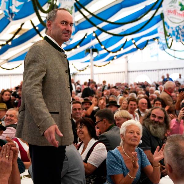 Der bayrische Wirtschaftsminister Hubert Aiwanger steht auf einer Bühne in einem Festzelt in blau-weißen Farben.