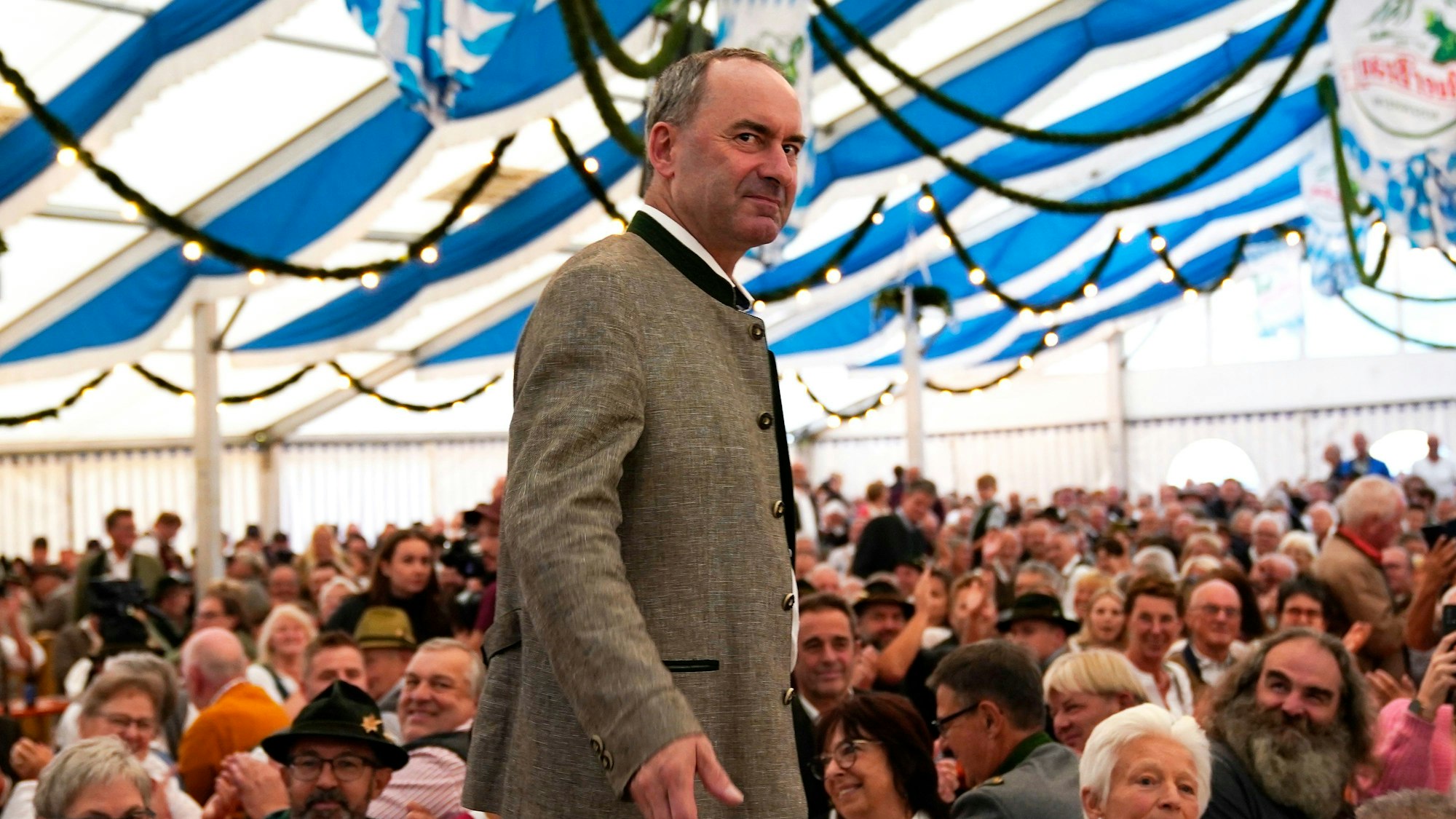 Der bayrische Wirtschaftsminister Hubert Aiwanger steht auf einer Bühne in einem Festzelt in blau-weißen Farben.
