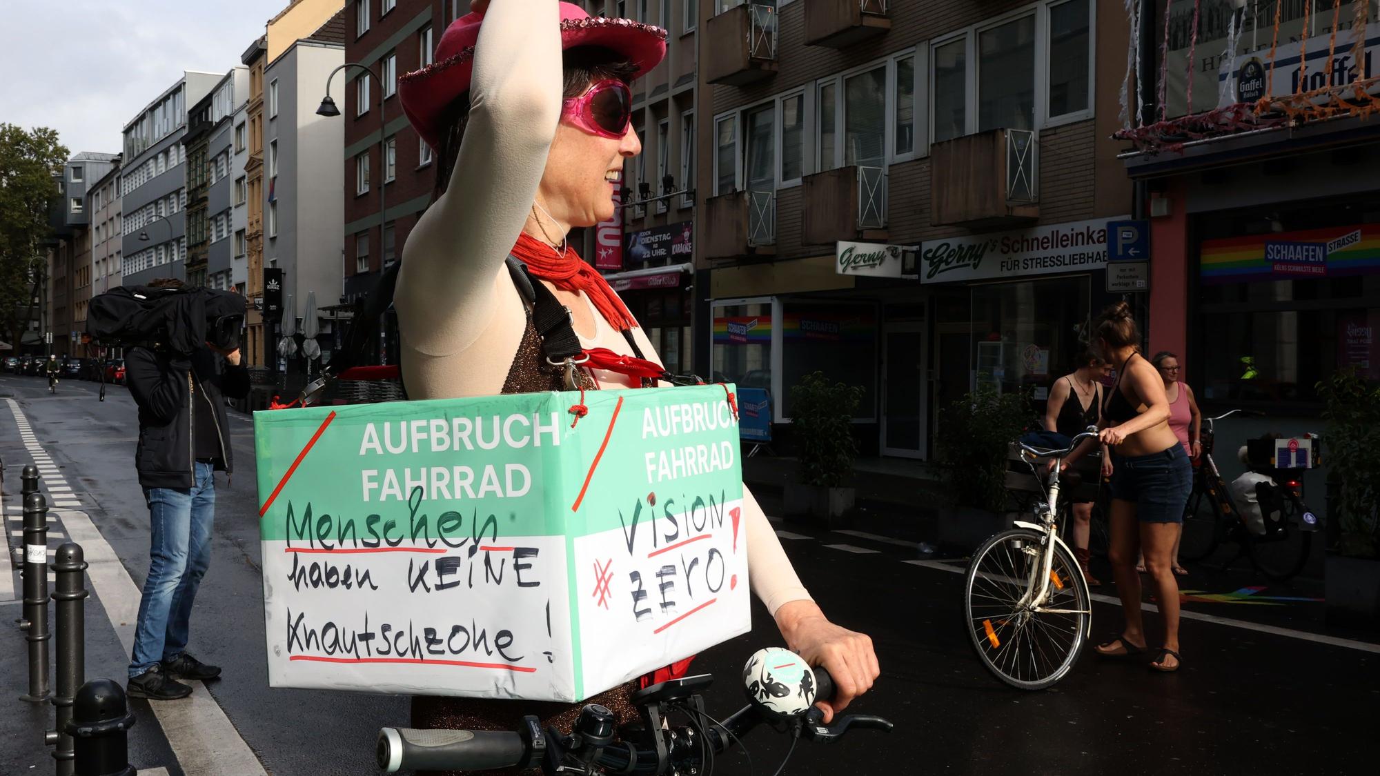 Eine verkleidete Frau trägt ein Demo-Schild um den Bauch.