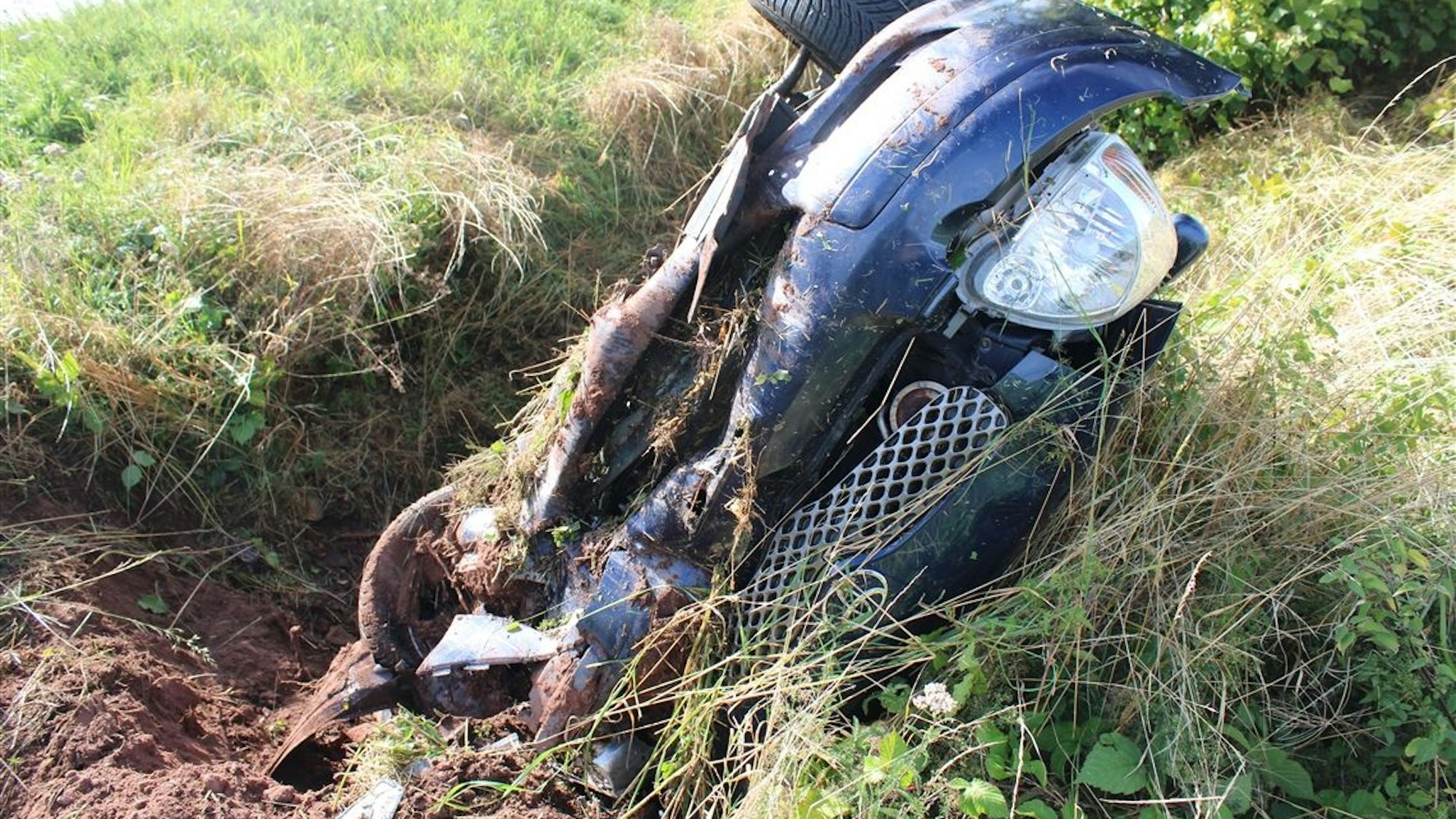 Nach einem Unfall bei Heimbach liegt ein zerstörtes Auto in einem Straßengraben.