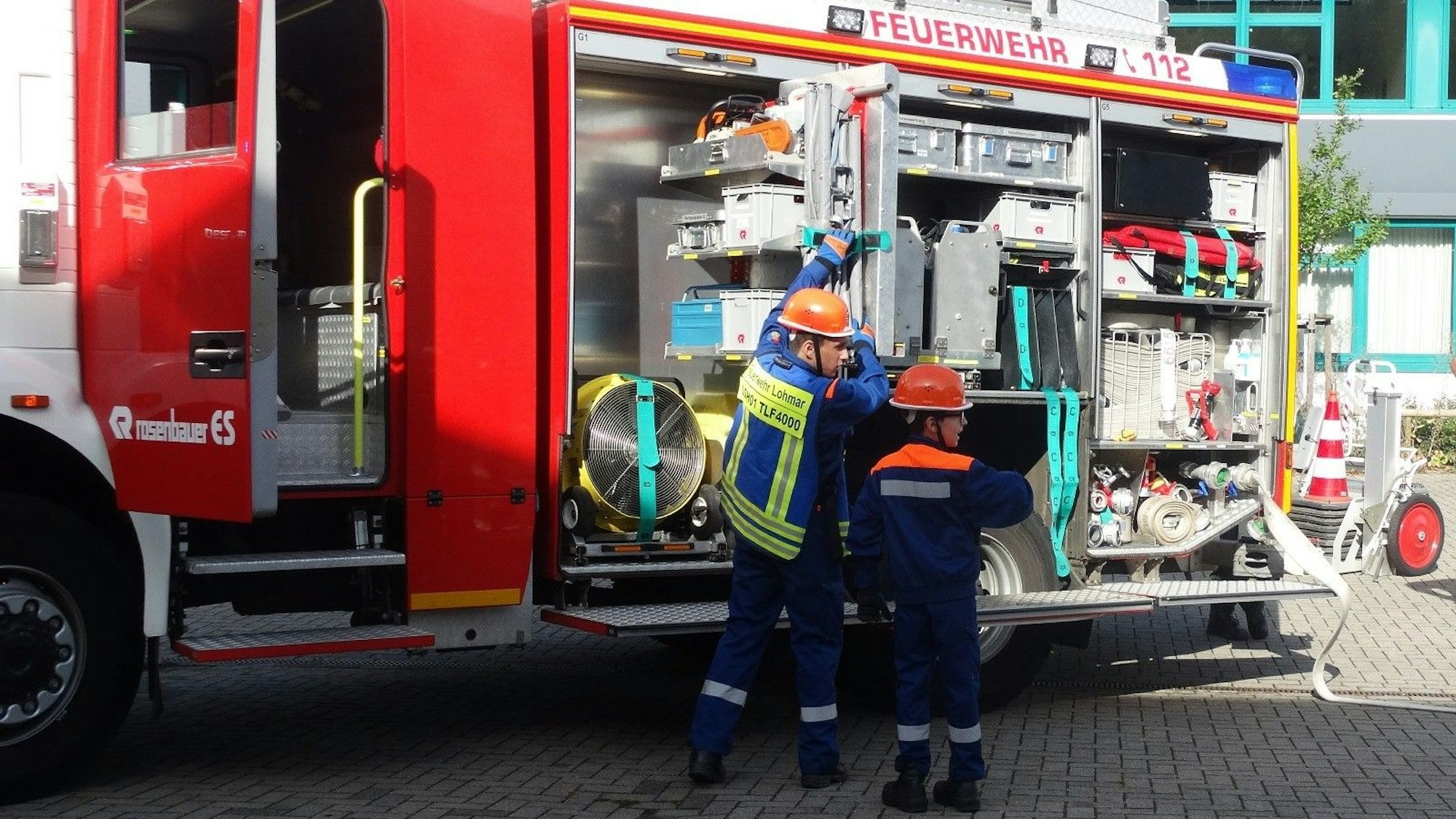 Zwei Jugendliche holen Gerät aus einem Löschfahrzeug.