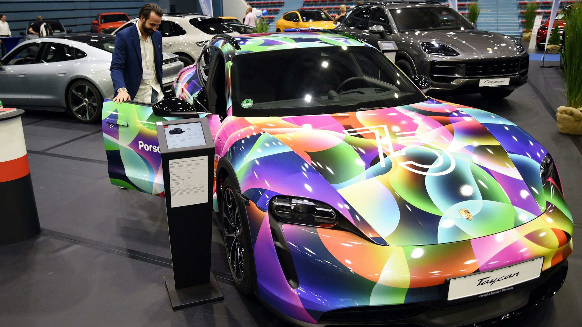 Ein Sportwagen steht neben vielen weiteren Autos in einer Sporthalle.