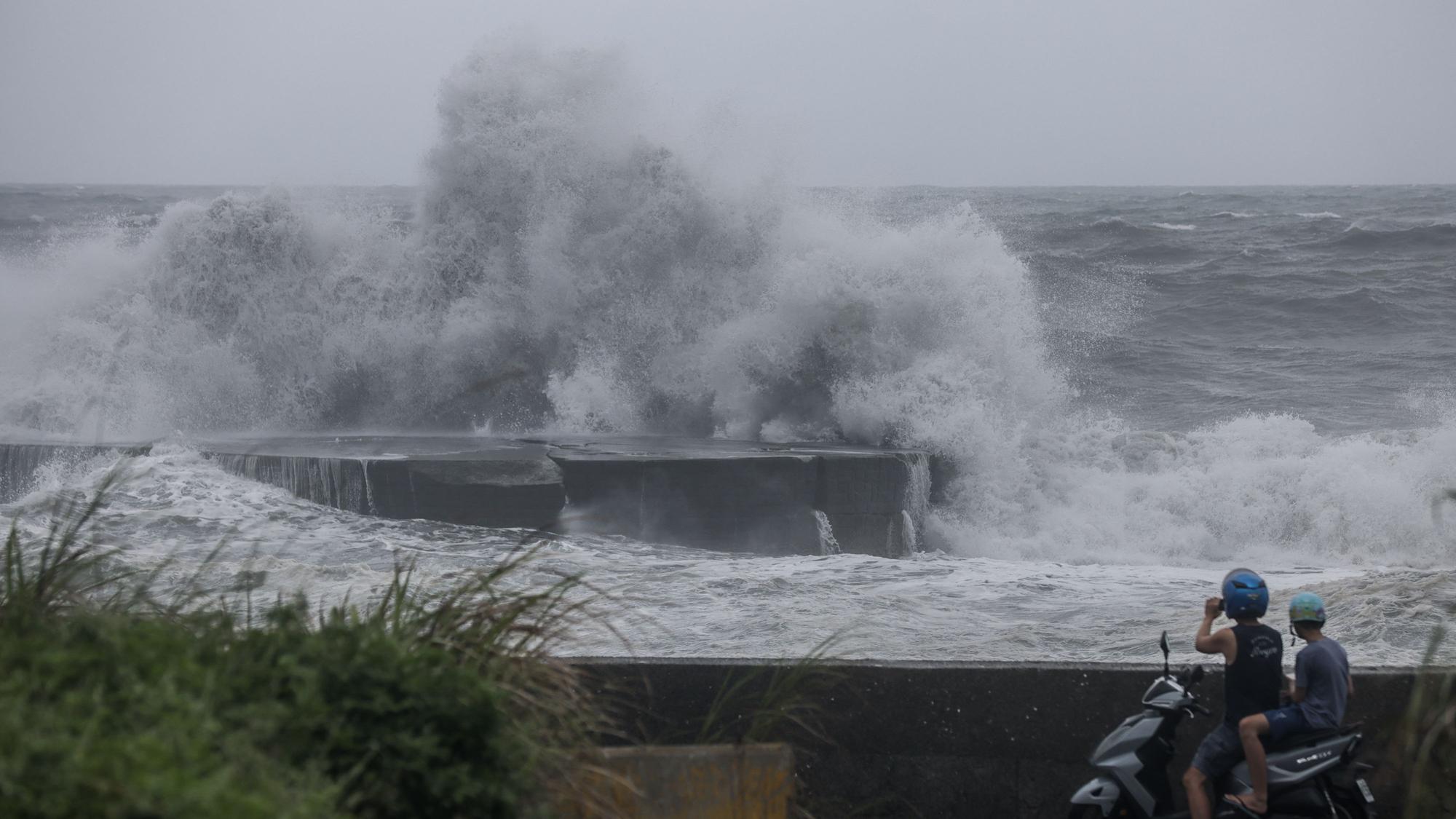 People watch huge waves in Yilan as Typhoon Haikui makes landfall in eastern Taiwan on September 3, 2023. (Photo by I-Hwa Cheng / AFP)