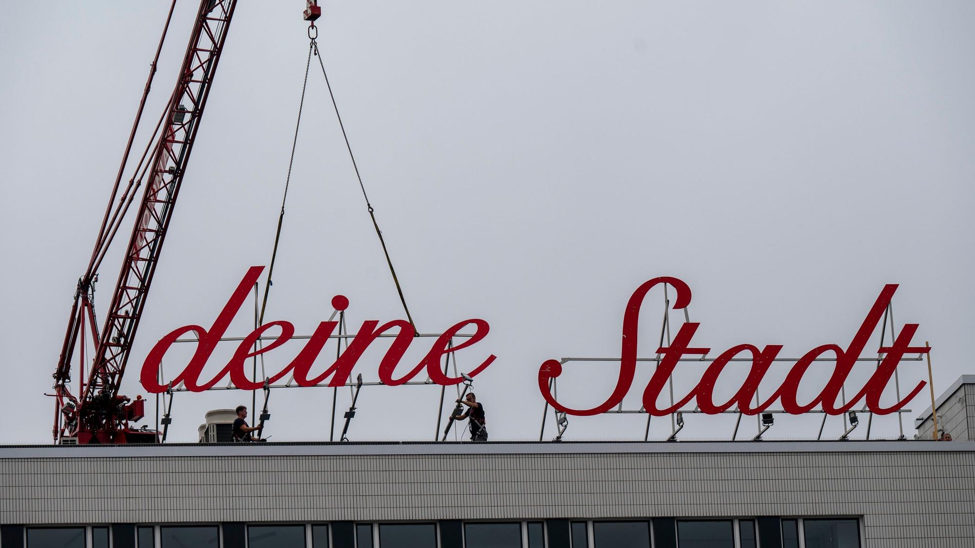 Der Schriftzug „Liebe deine Stadt“ wird mit einem Kran wieder installiert.