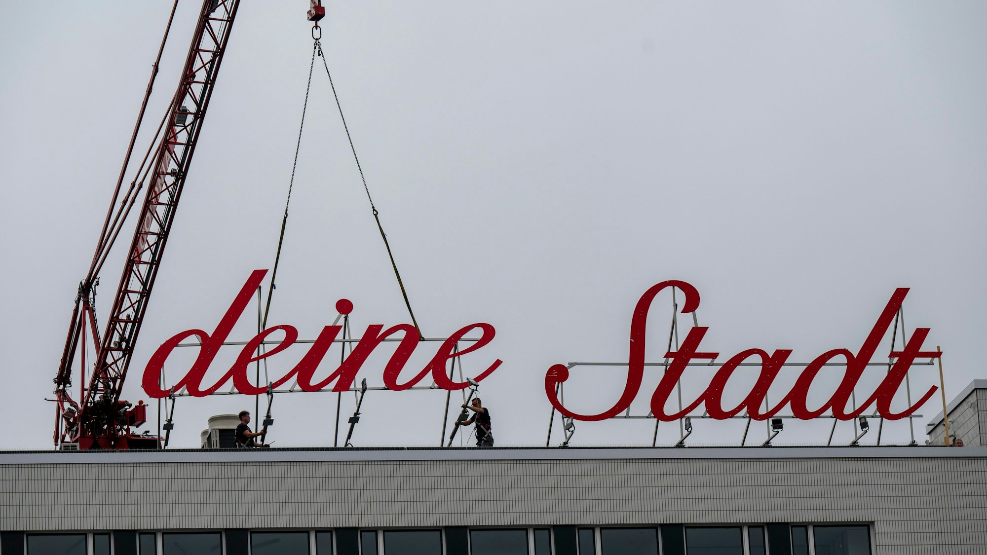 Der Schriftzug „Liebe deine Stadt“ wird mit einem Kran wieder installiert.