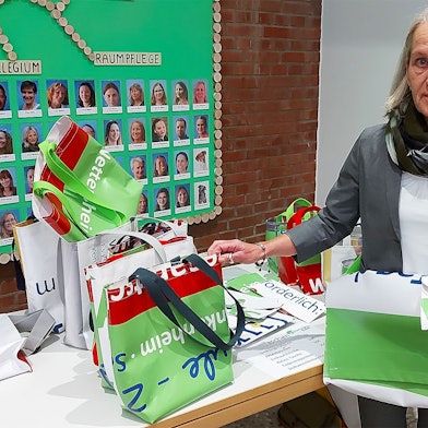 Elisabeth Weißkopf zeigt die umweltfreundlichen Artikel, die aus alten Plakaten der Gesamtschule Eifel hergestellt wurden.