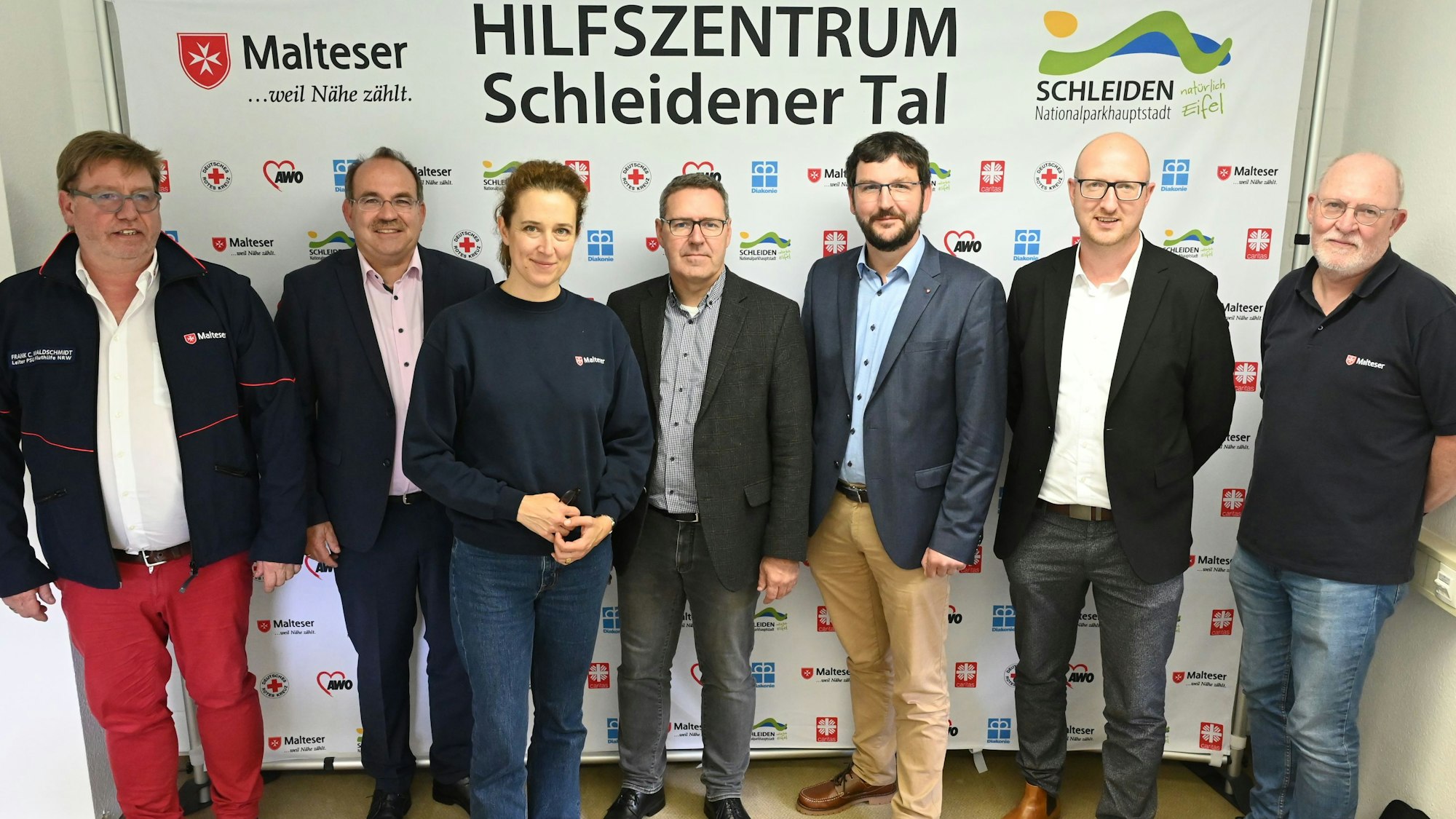 Sechs Männer und eine Frau stehen vor dem Plakat des Hilfszentrums Schleidener Tal: Frank C. Waldschmidt (v.l.), Dr. Ralf Nolten, Dr. Sophie von Preysing, Prof. Harald Karutz, Wolfgang Heidinger, Ingo Pfennings und Gerd Sebastian.
