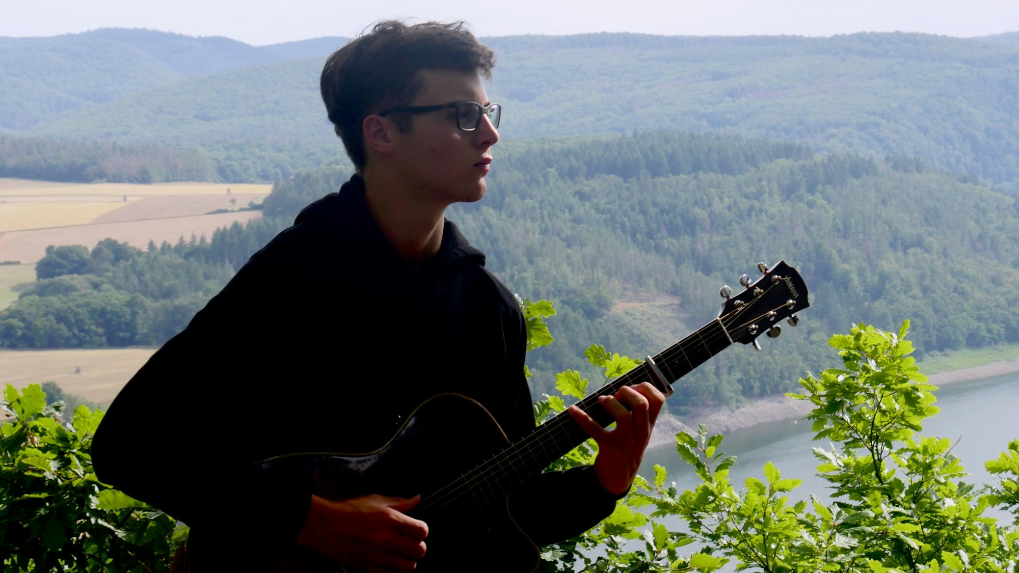 Vincent Kneip mit seiner Gitarre vor einem Landschaftspanorama.
