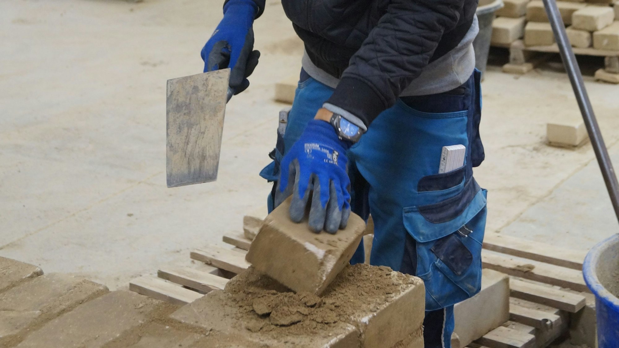 Ein Auszubildender im Baugewerbe baut eine Mauer.