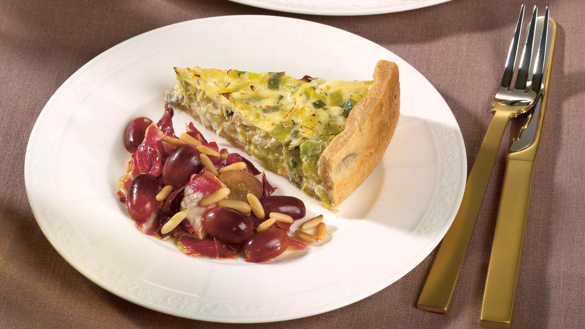 Stück Quiche mit Traubensalat auf einem Teller