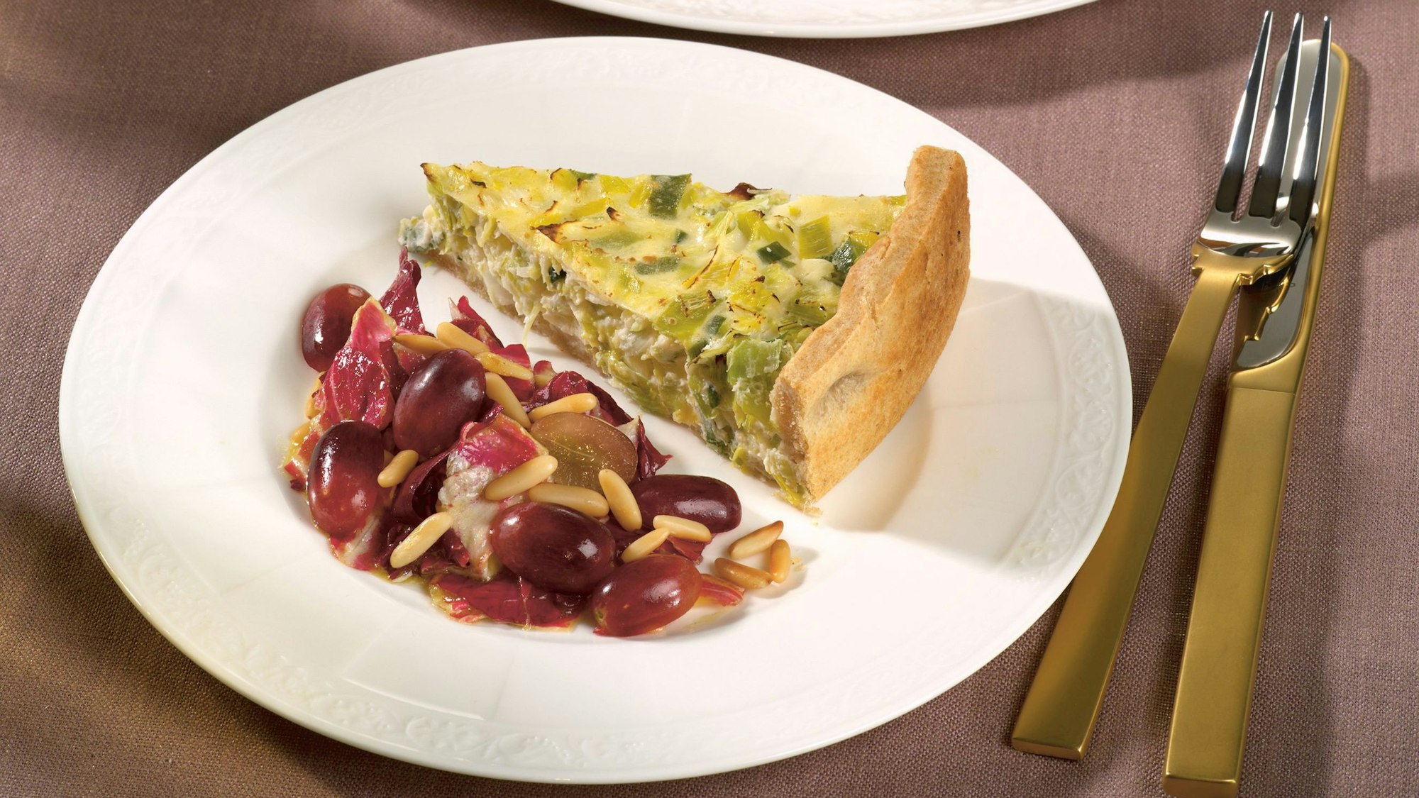 Stück Quiche mit Traubensalat auf einem Teller