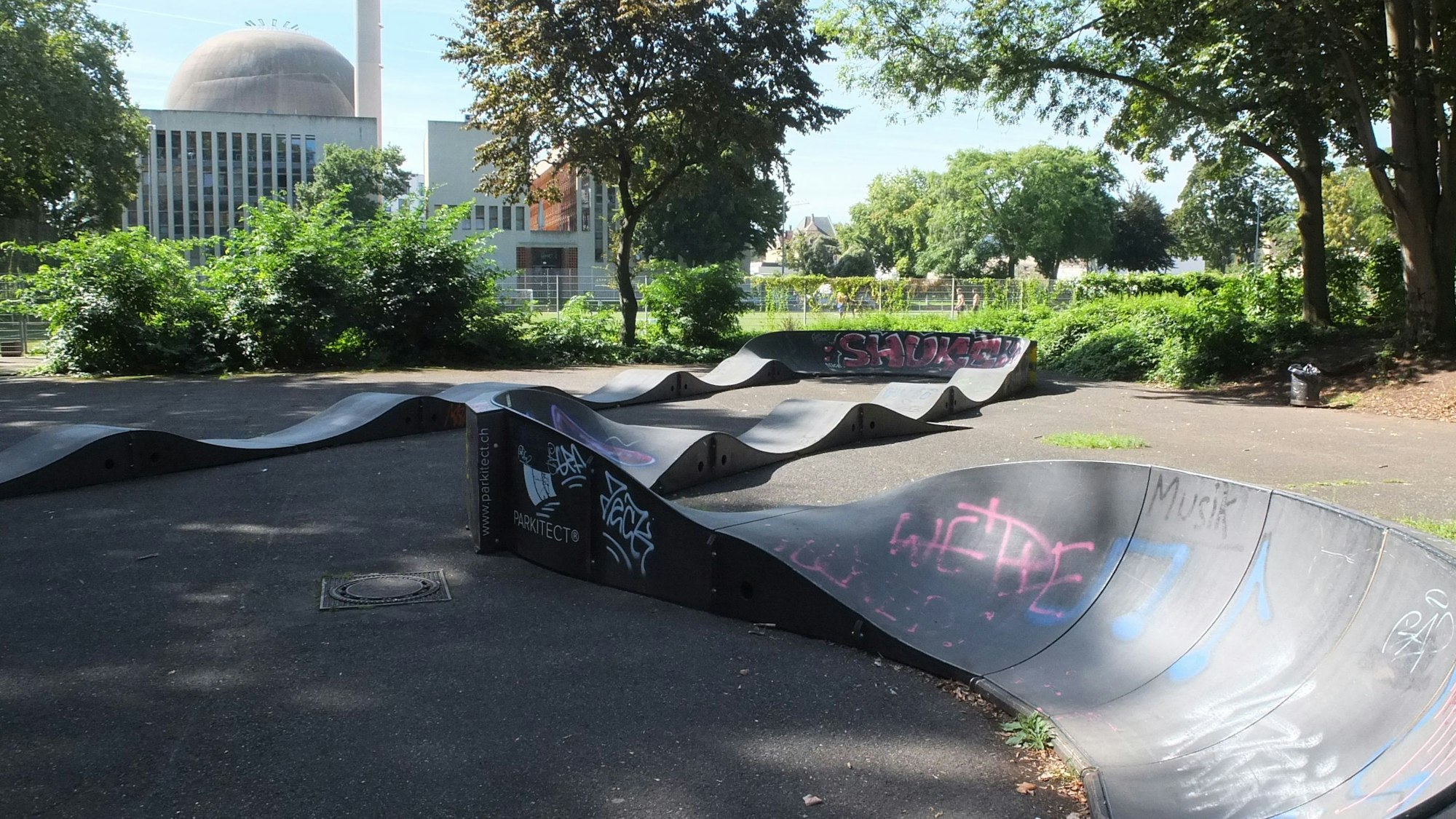 Wellenförmige Elemente stehen auf einer Asphaltfläche, hier können sich Skater austoben.