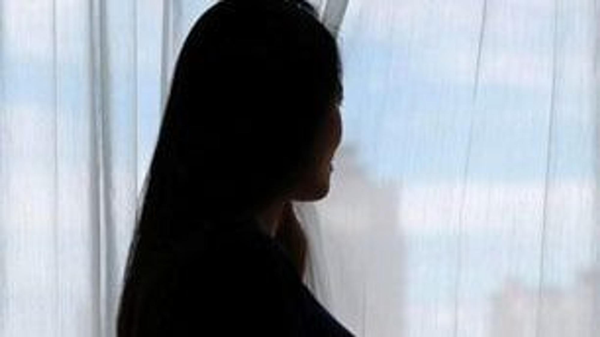 Eine schwangere Frau steht im Gegenlicht. Es ist nur die Silhouette zu sehen.
