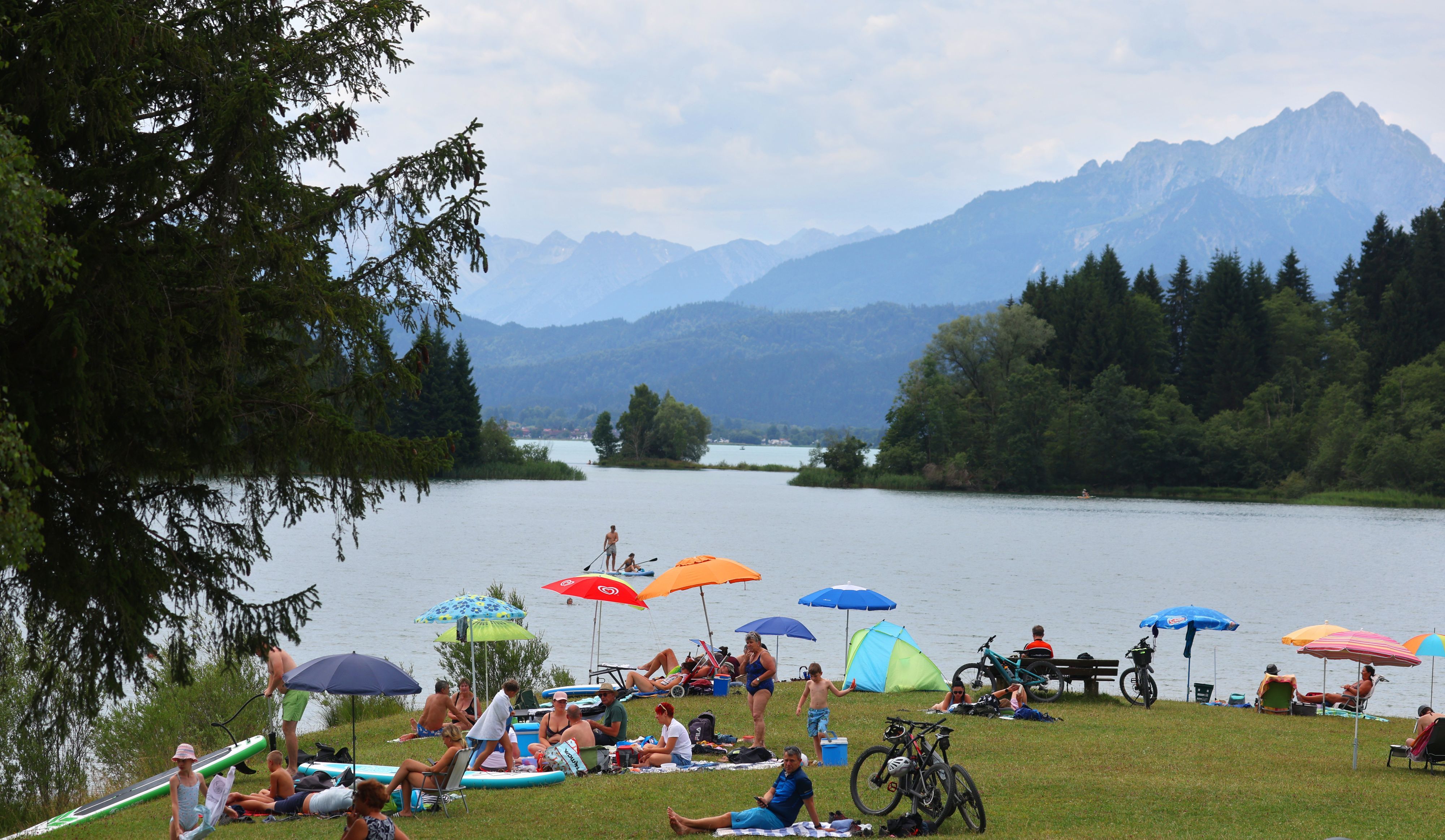 08.07.2023, Bayern, Roßhaupten: Ausflügler genießen das sommerliche Wetter in einem Strandbad des am Alpenrand gelegenen Illasbergsees. Foto: Karl-Josef Hildenbrand/dpa +++ dpa-Bildfunk +++
