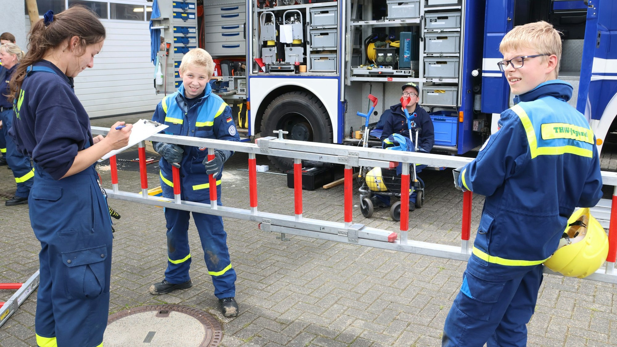 Kritisch und sorgfältig prüft Laura Willach von der Bezirksjugend des Technischen Hilfswerks in Waldbröl die Arbeit von Leonard Bornträger (links) und Maximilian Thurau aus Bergneustadt. Soeben haben die beiden Jungs Leitern zusammengesteckt.