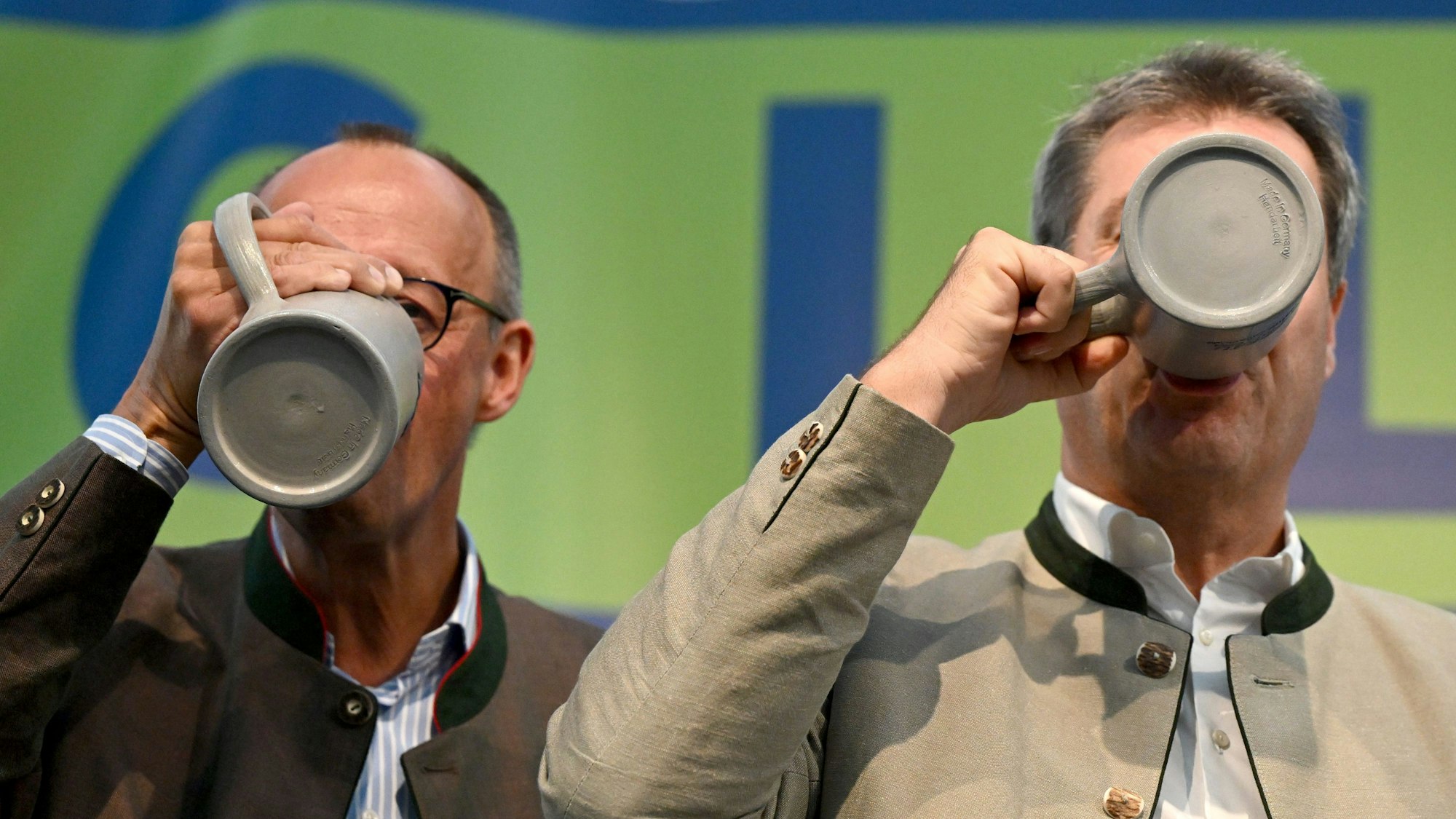 04.09.2023, Bayern, Abensberg: Friedrich Merz (l), Bundesvorsitzender der CDU, und Markus Söder (CSU), Ministerpräsident von Bayern, trinken beim Politischen Frühschoppen Gillamoos auf der Bühne aus Bierkrügen. Das Gillamoos ist eines der größten und ältesten Volksfeste Niederbayerns und bietet traditionell einen politischen Schlagabtausch der Parteien. Foto: Sven Hoppe/dpa +++ dpa-Bildfunk +++