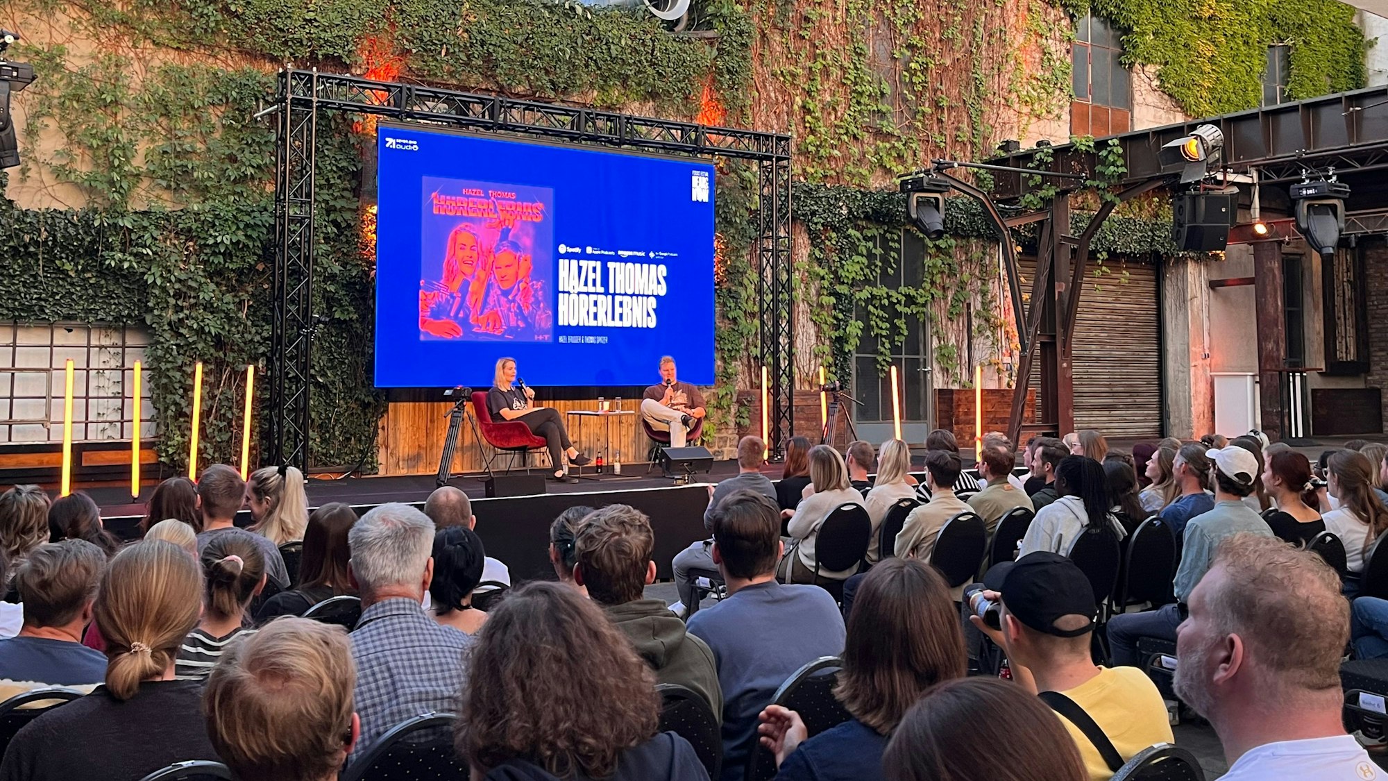 Zwei Podcaster auf der Bühne.