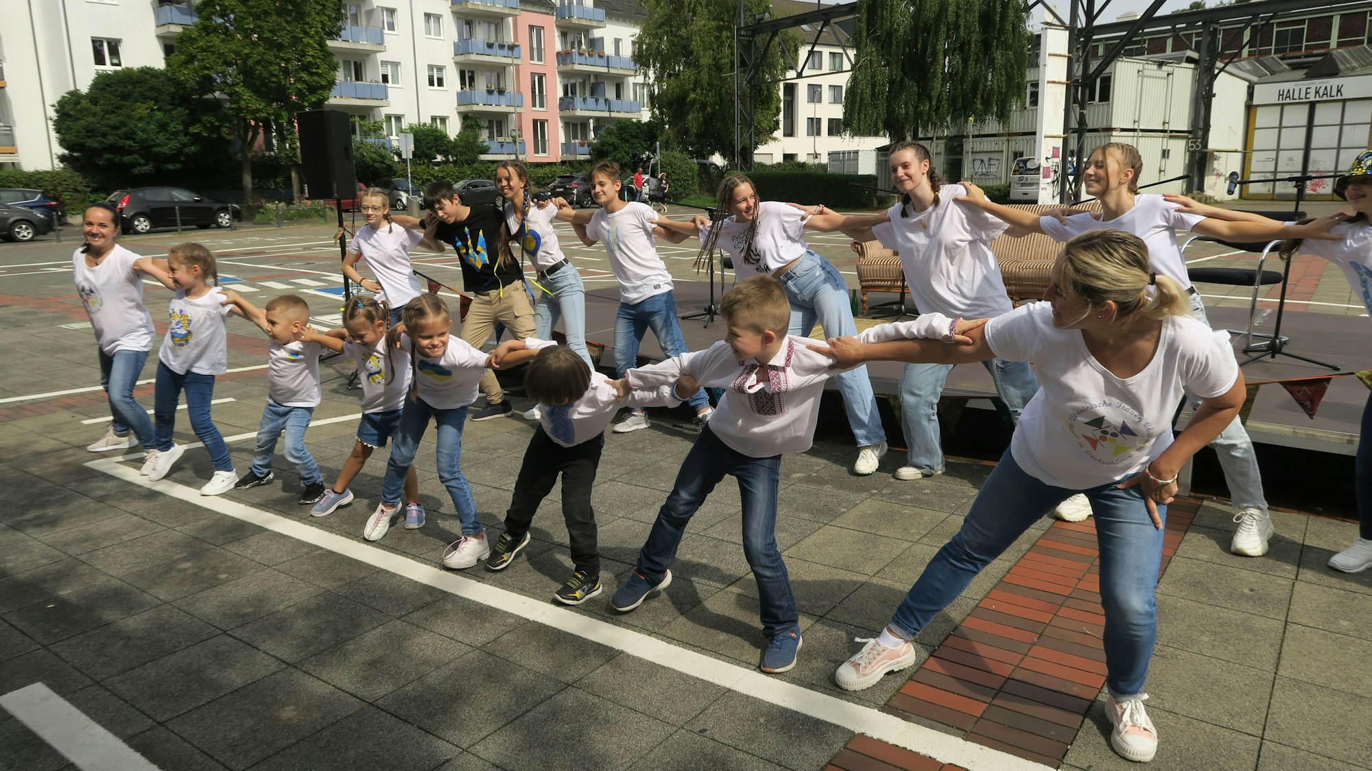 Junge Mädchen halten sich an den Schultern, neigen sich synchron zur Seite.