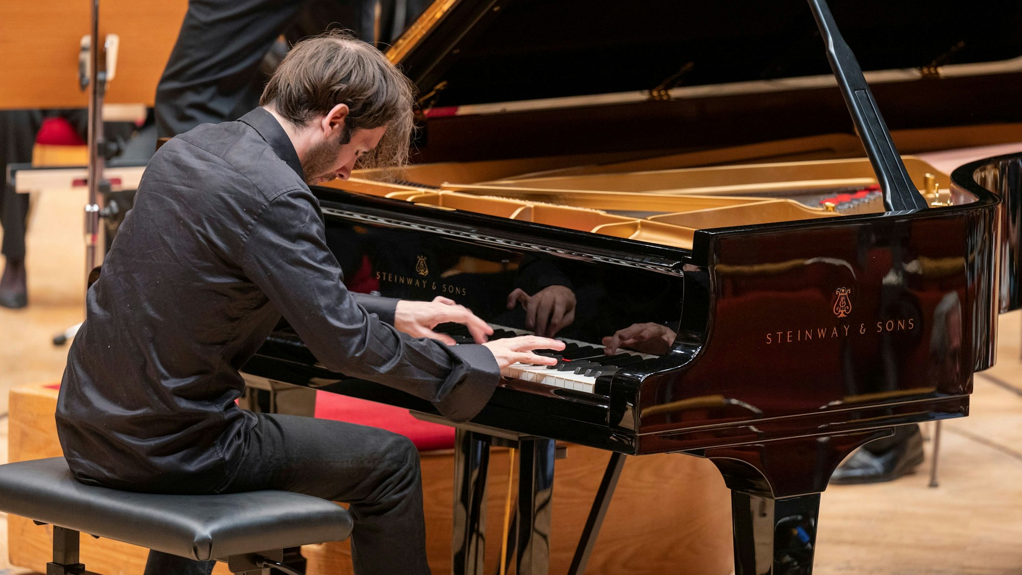 Das Bild zeigt Alexandre Kantorow beim Spielen. Hemd und Hose sind so schwarz wie sein Flügel.