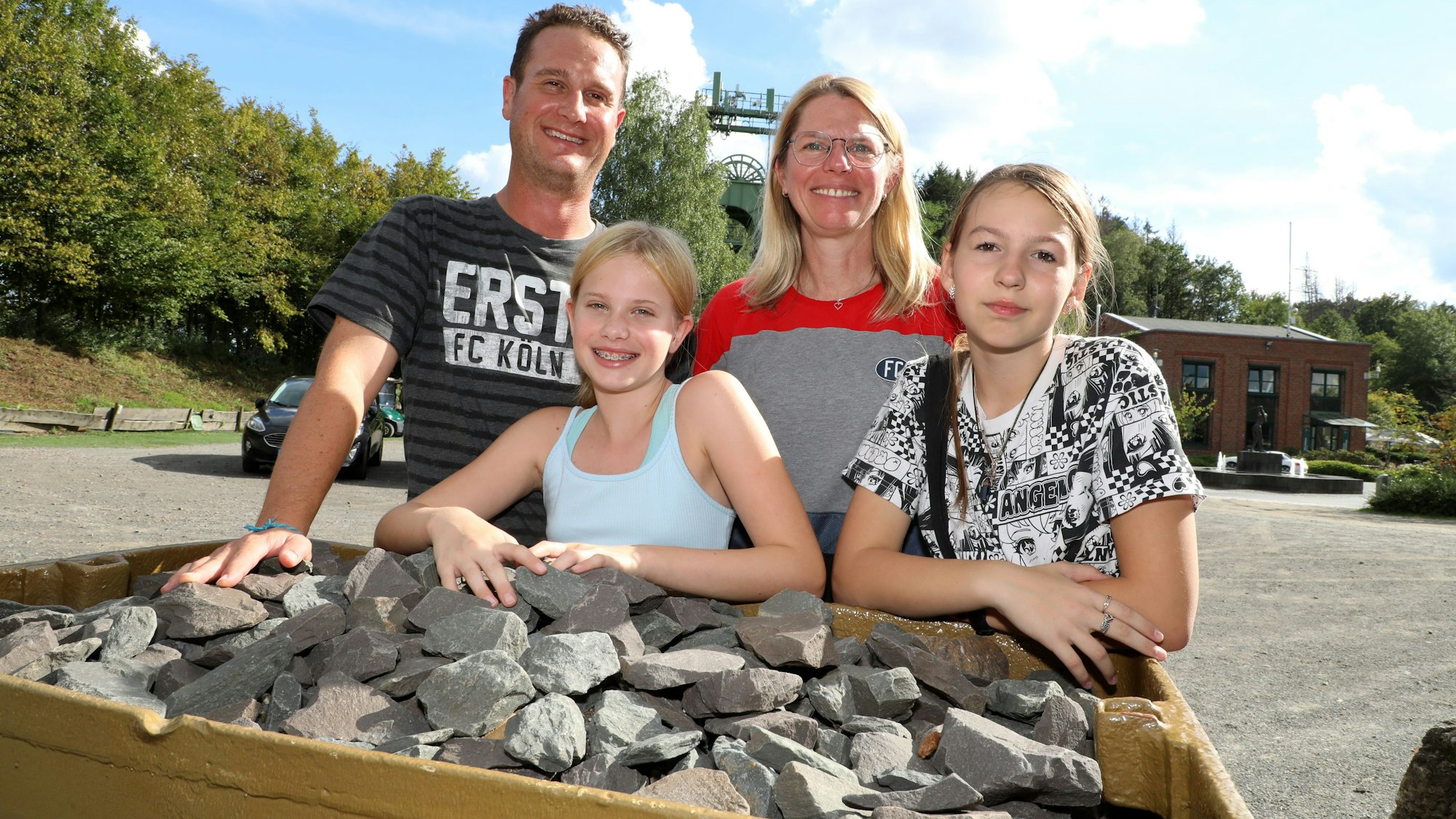 Eine Familie steht mit ihrer Gastschülerin aus Butscha hinter einem mit Schotter beladenen Förderwagen auf dem Lüderich.