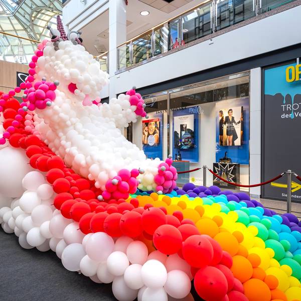 Ein Einhorn mit Regenbogen aus Luftballons steht im Erdgeschoss eiens großen Einkaufszentrums.