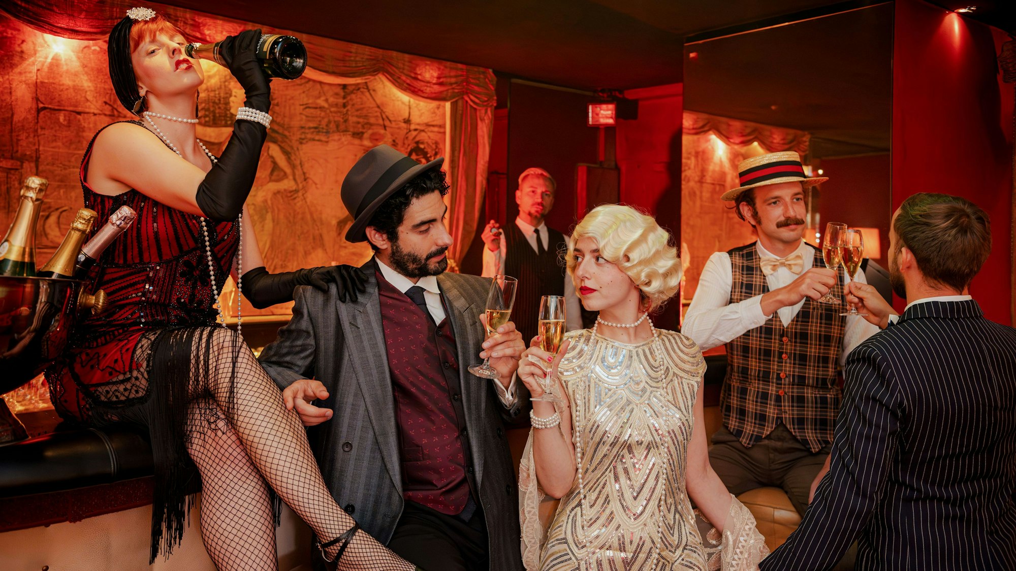 Menschen stehen in 20er-Jahre-Kleidung in einer Bar.
