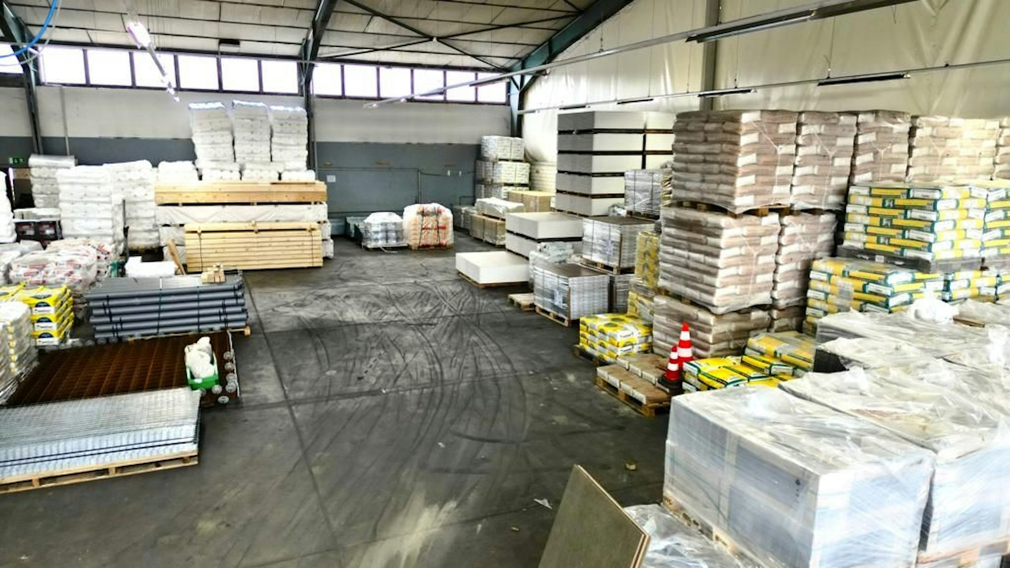 In einer Lagerhalle liegen Säcke und andere Baustoffe auf Paletten.
