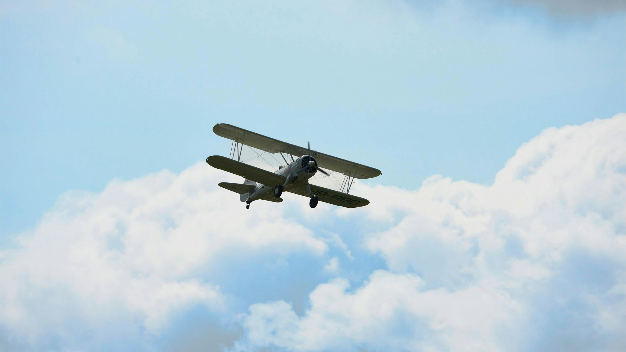 Doppeldecker gegen blauen Himmel mit Wolkenstimmung während Flugmeeting. Schweiz