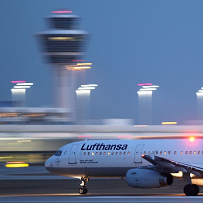 Ein Airbus A321 der deutschen Fluggesellschaft Lufthansa startet auf einem Flughafen. Im Hintergrund sind verschwommen Scheinwerfer der Startbahn und der Flughafentower zu sehen. (Symbolbild)
