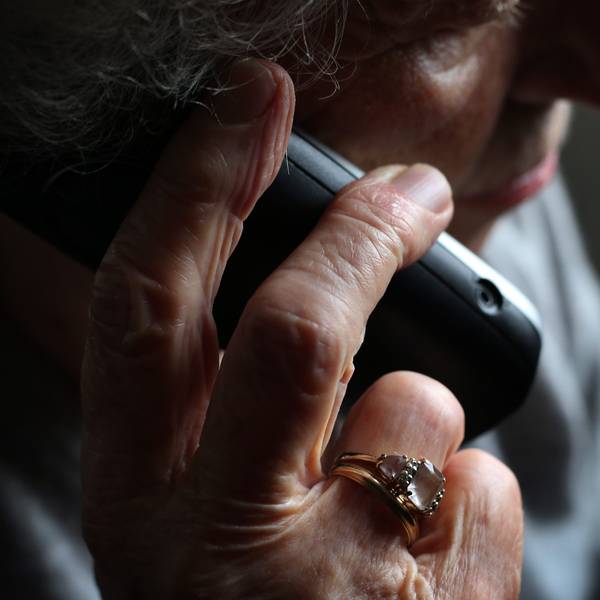 Das Foto zeigt eine ältere Person am Telefon.