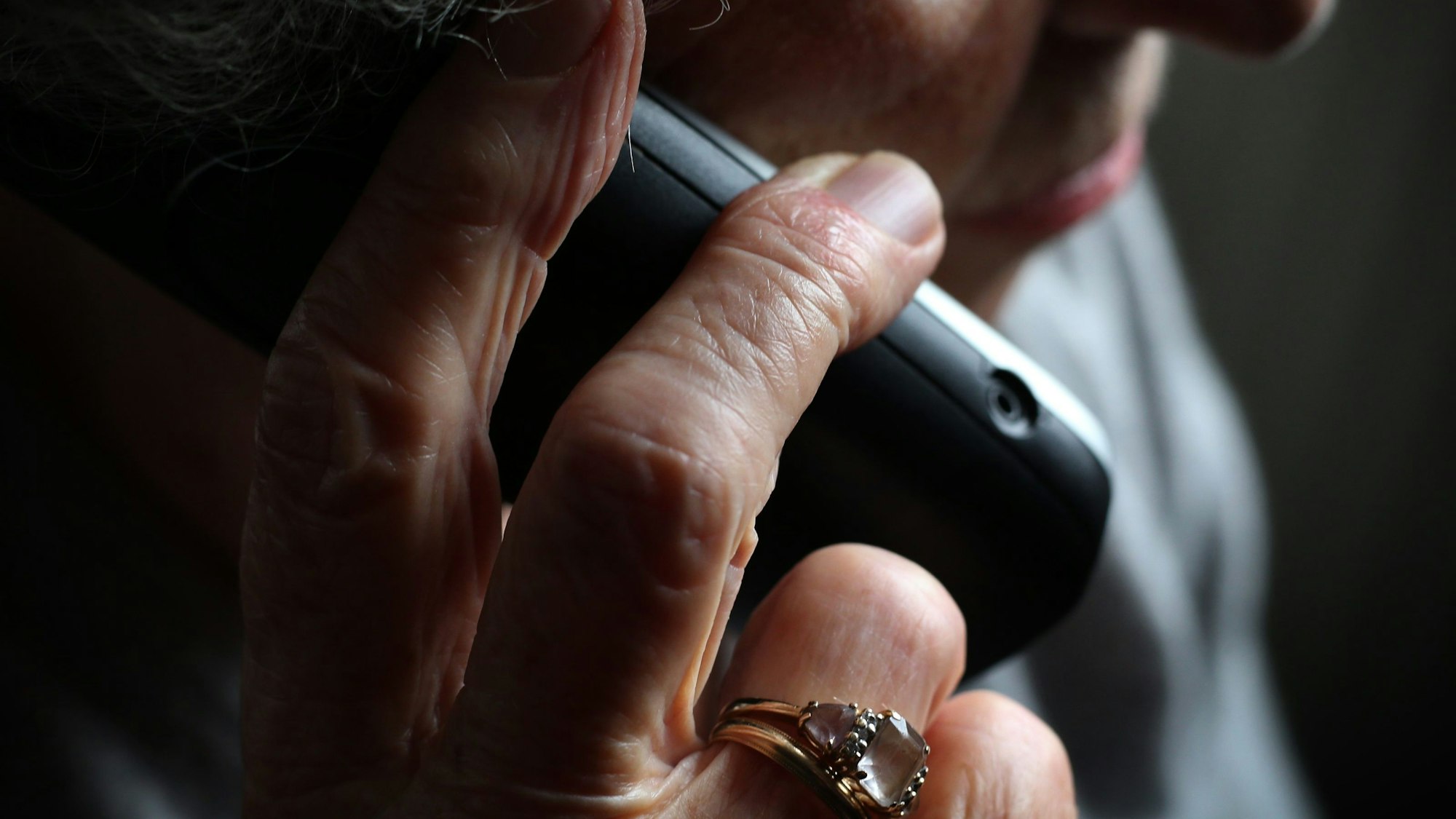 Das Foto zeigt eine ältere Person am Telefon.