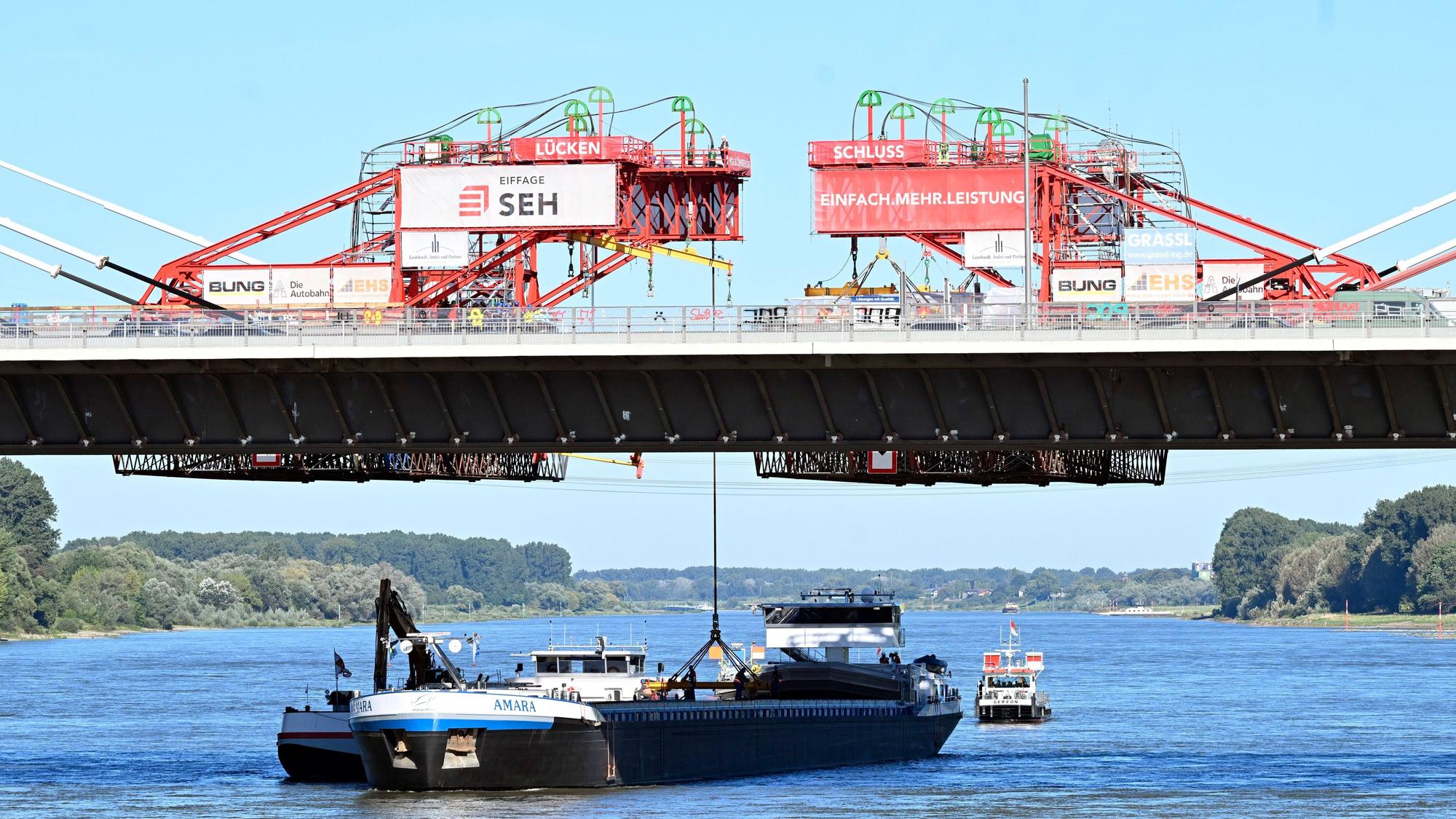 05.09.2023, Nordrhein-Westfalen, Leverkusen: Ein Kran hebt das letzte Bauteil zur «Brückenhochzeit» an den Neubau der Leverkusener Rheinbrücke. Ungefähr sechs Jahre nach Beginn der Arbeit ist die Brücke nun über dem Rhein verbunden. Nach Fahrbahneinbringung und diversen Sicherheitsvorkehrungen wird die Brücke ca Januar 2024 für den Verkehr freigegeben. Dann wird die alte marode Brücke abgerissen und mit den Arbeiten zum zweiten Teil gestartet. Völlige Baufertigstellung soll dann 2027 sein. Foto: Roberto Pfeil/dpa +++ dpa-Bildfunk +++