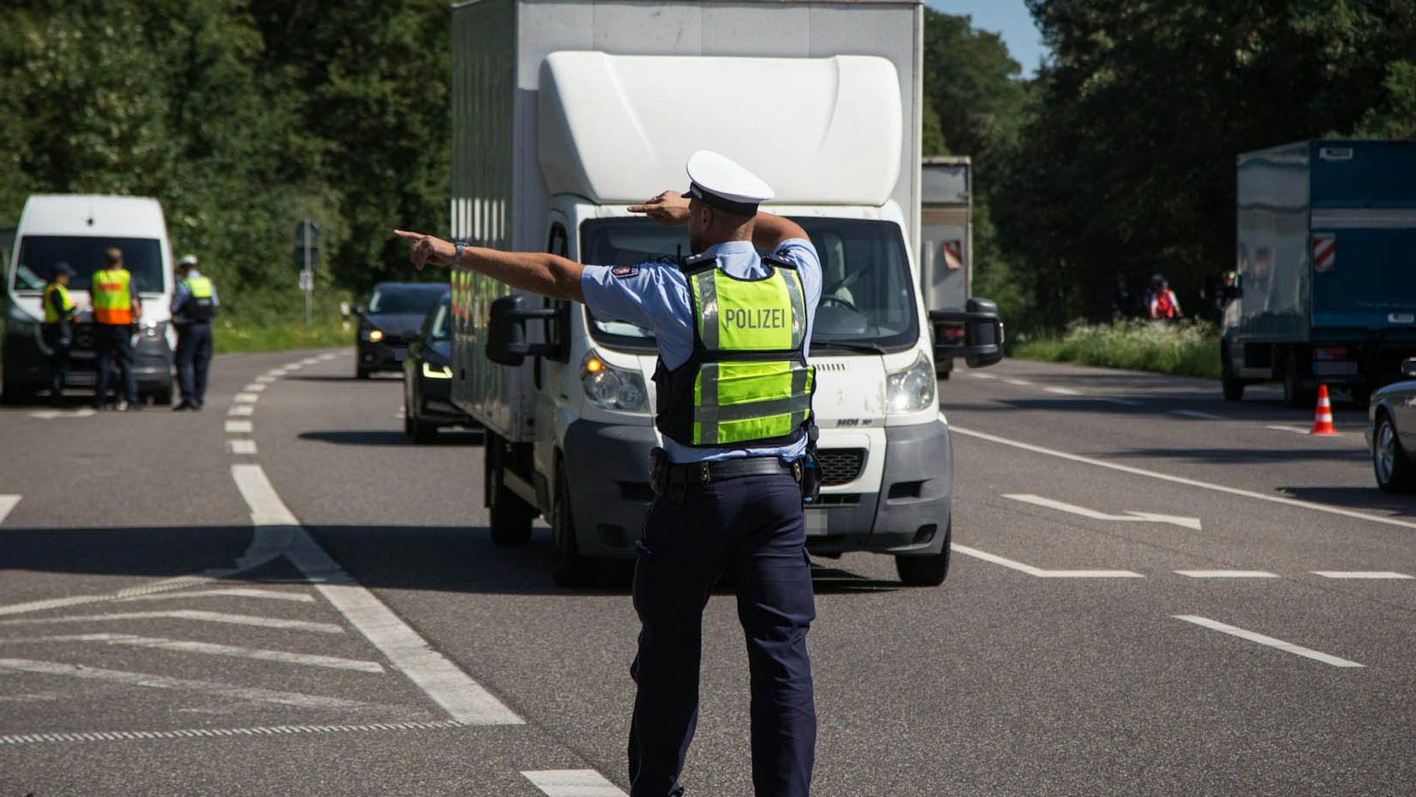 Das Bild zeigt einen Polizisten, der einen Kleintransporter auf den Seitenstreifen winkt.