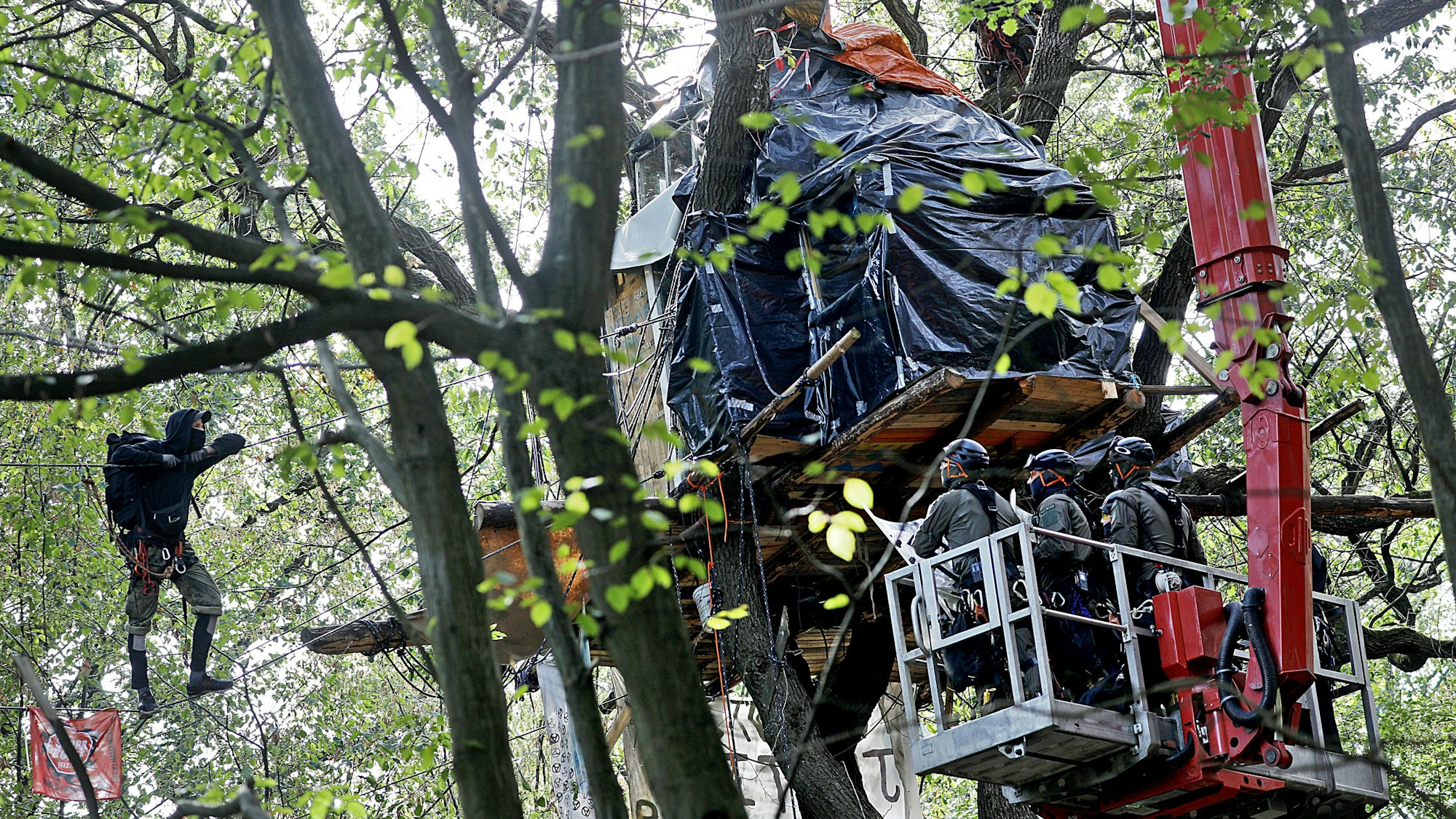 17.09.2018, Nordrhein-Westfalen, Kerpen: Polizisten nähern sich in einem Hubwagen einem Baumhaus.