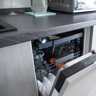 Ein Mann öffnet eine Spülmaschine in einer Küche.