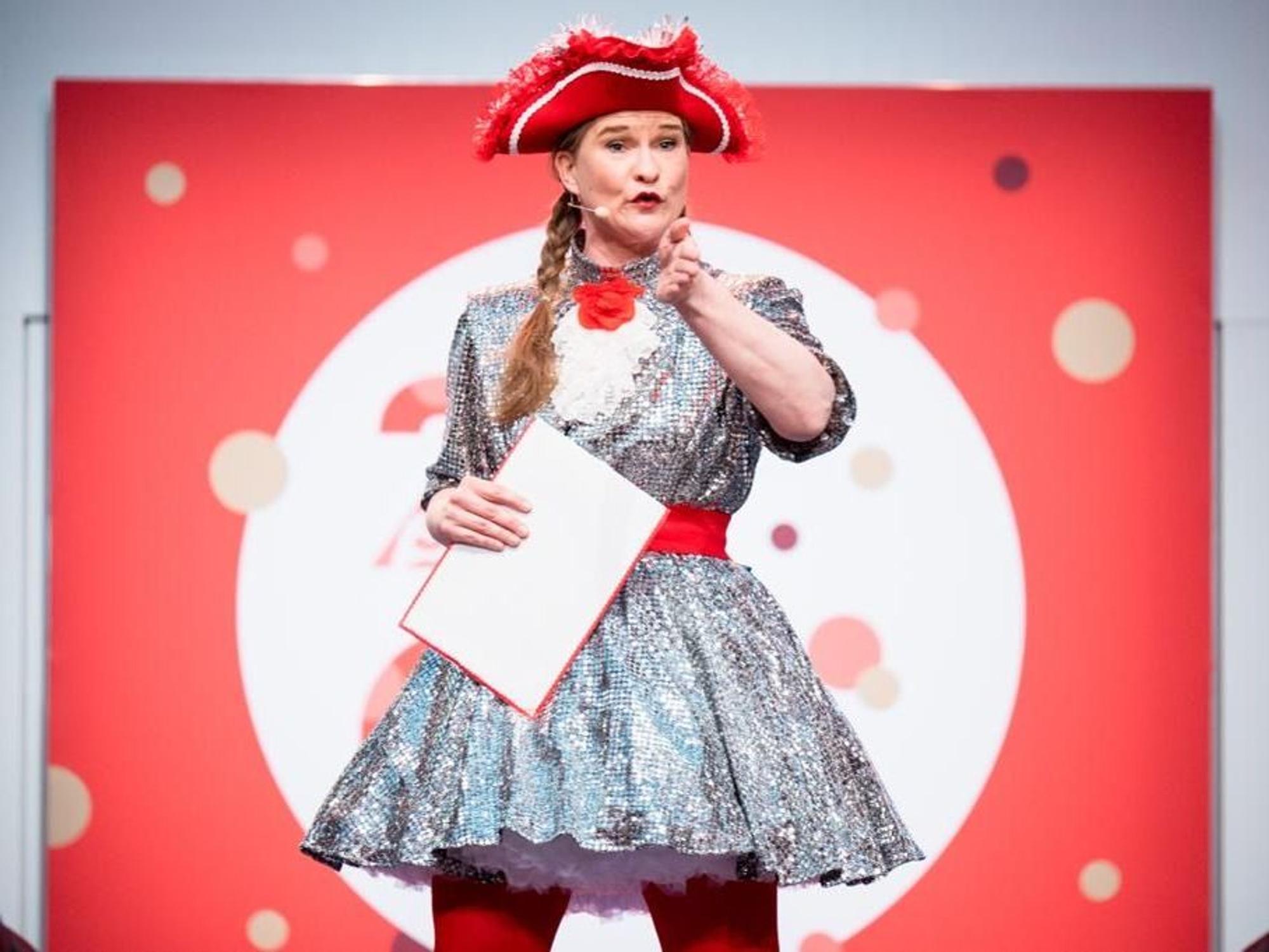 Vera Passy im glitzernden Kleid und mit rotem Hut.