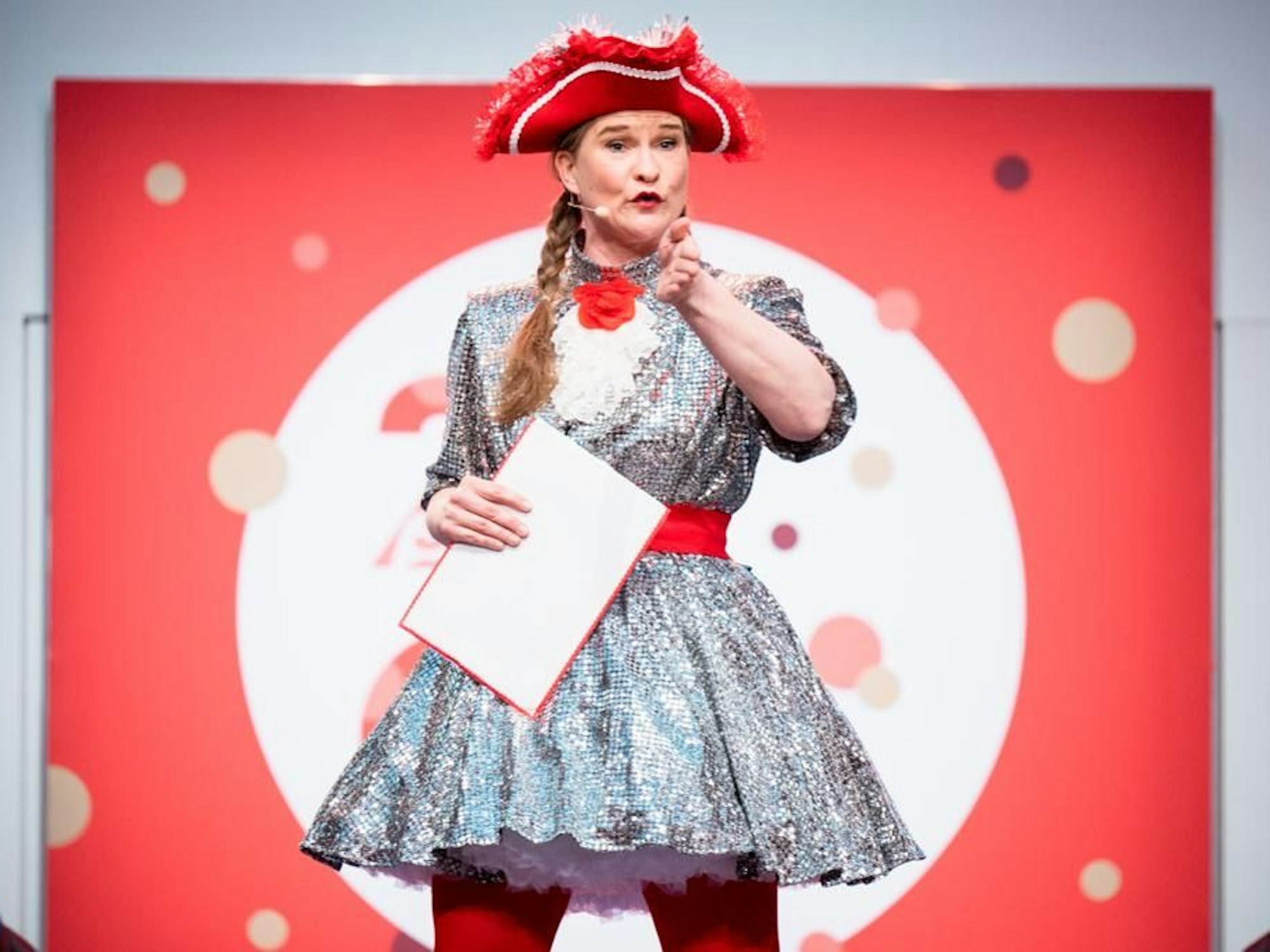 Vera Passy im glitzernden Kleid und mit rotem Hut.