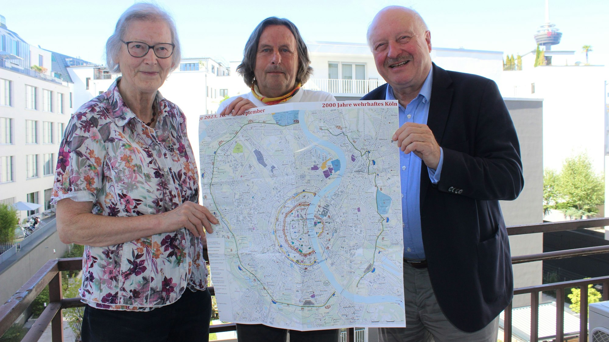 Drei Personen halten eine Karte hoch und lächeln in die Kamera.