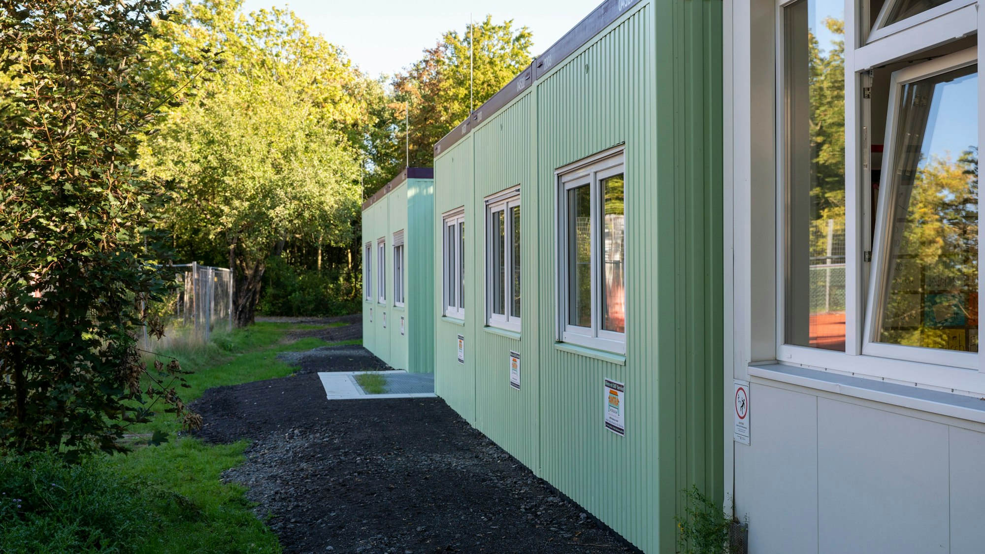 Vier Schulcontainer auf einem Schulhof.