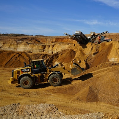 Das Bild zeigt einen Radlader und ein Förderband im Tagebau.
