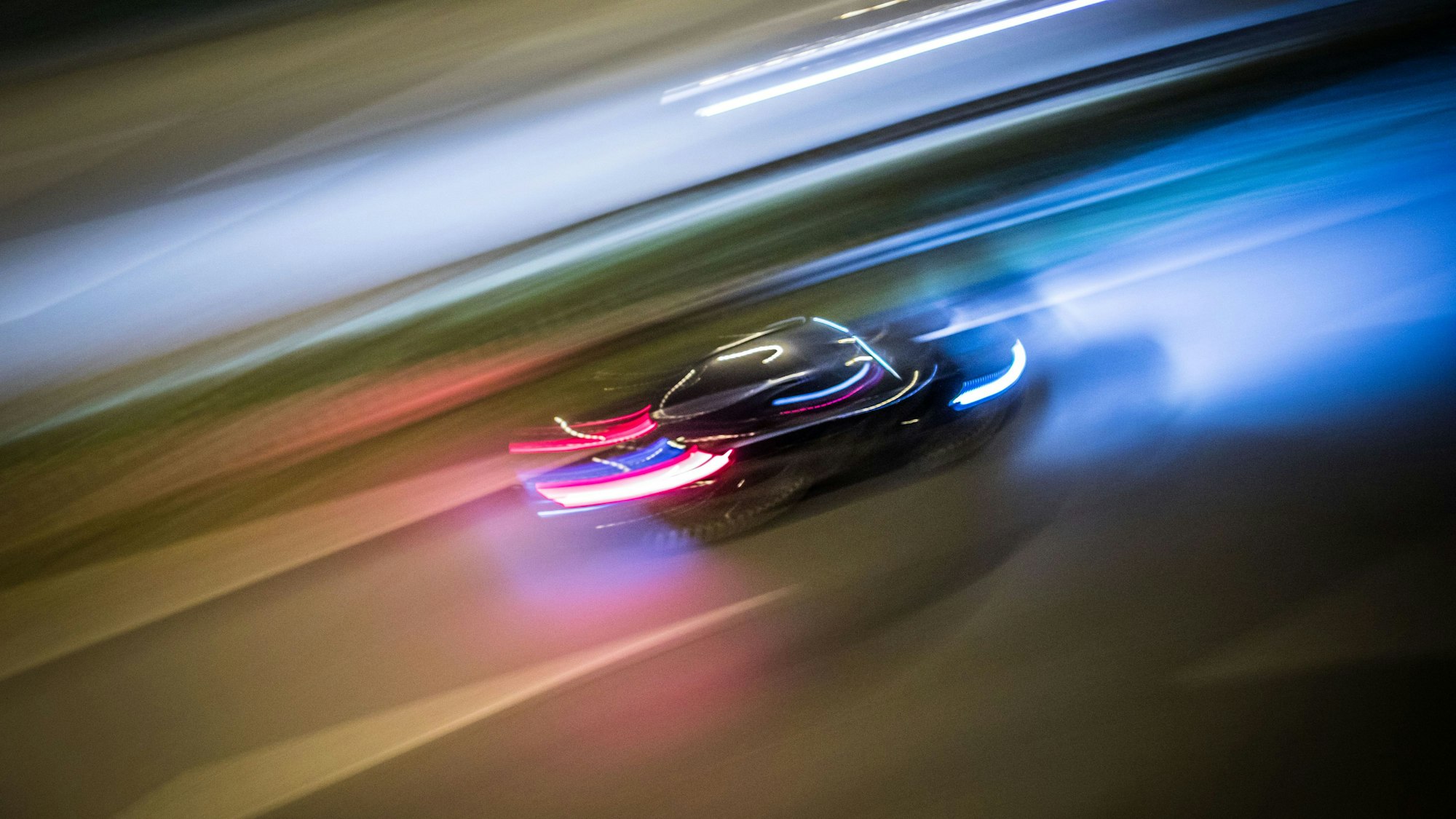 Ein Auto fährt sehr schnell durch die Nacht, die Konturen verschwimmen.