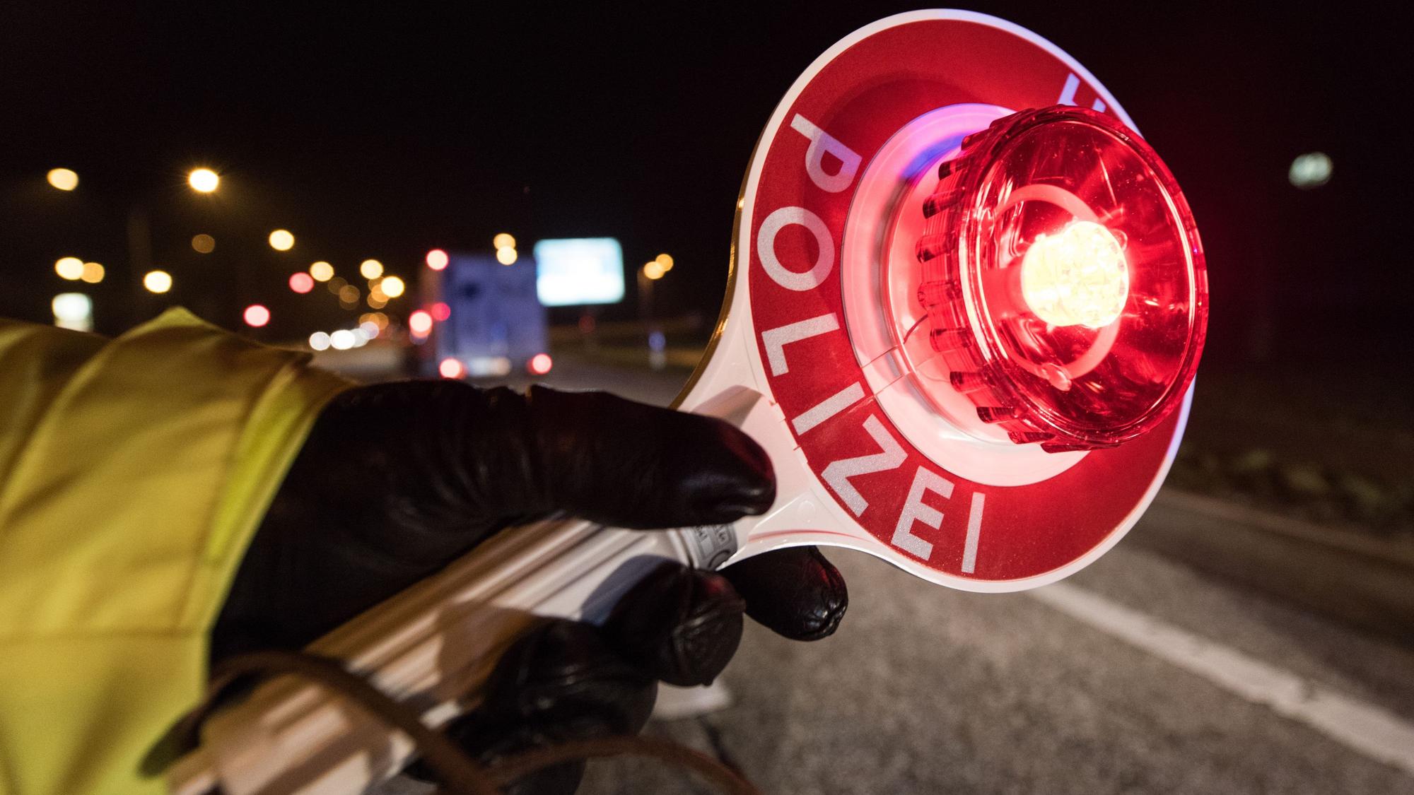 Ein Polizist hält am 03.12.2016 während einer Verkehrskontrolle mit einer Haltekelle Fahrzeuge an.