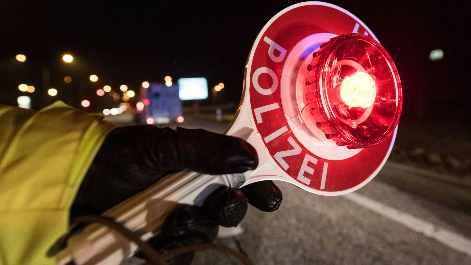 Ein Polizist hält während einer Verkehrskontrolle in Freiburg (Baden-Württemberg) mit einer Haltekelle Fahrzeuge an.