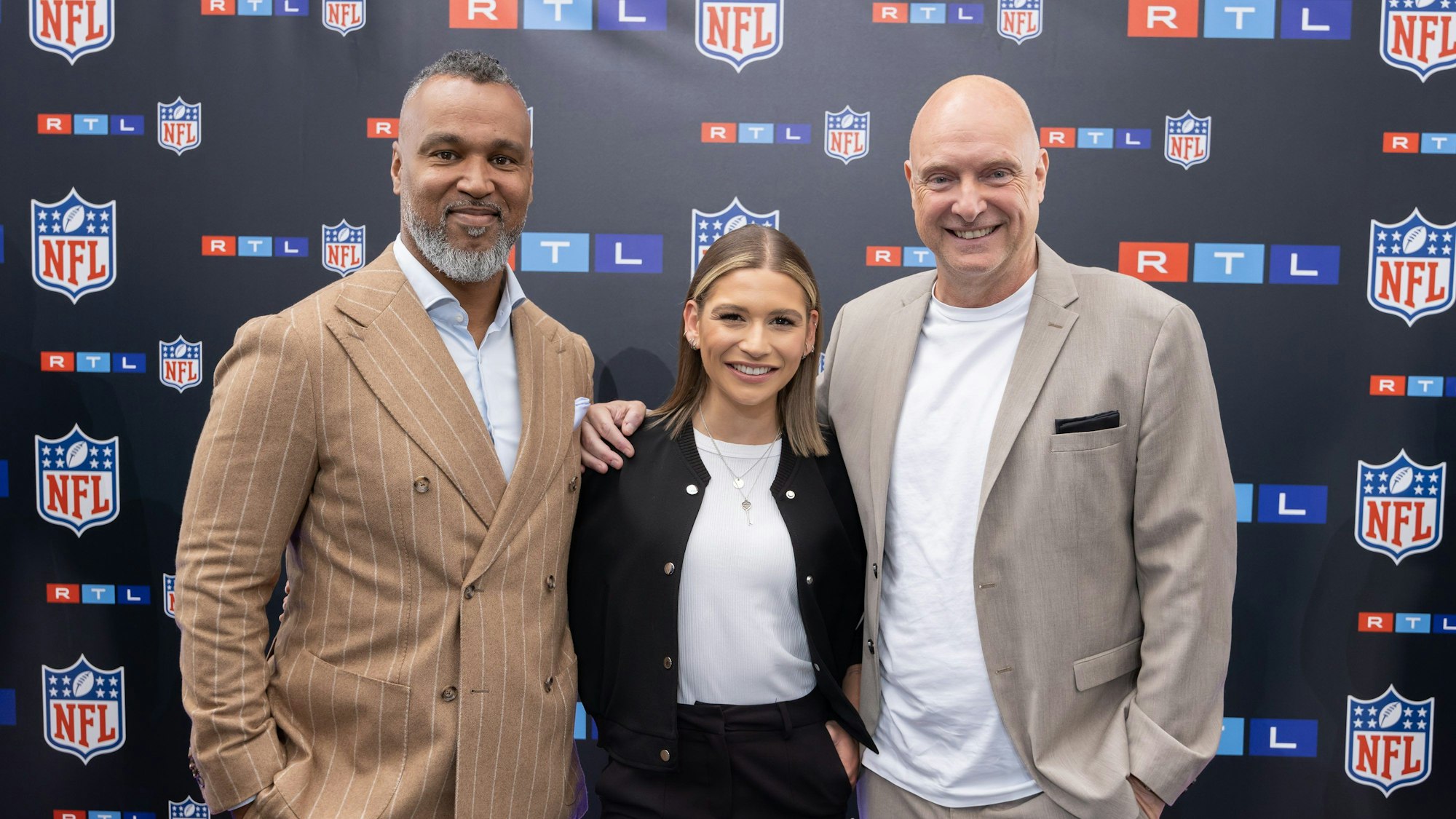 TV-Experte Patrick Esume (l) und die TV-Moderatoren Jana Wosnitza und Frank Buschmann stehen beim Presseevent zusammen. Die RTL-Gruppe beginnt ihre NFL-Übertragungen.