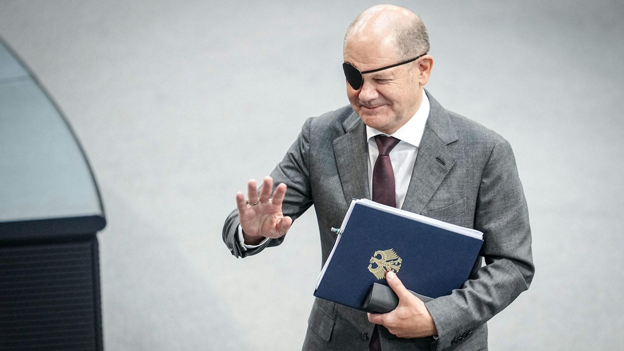 Bundeskanzler Olaf Scholz (SPD) mit Redemanuskript im Bundestag. Nach einem Sturz beim Joggen trägt er noch eine Augenklappe.